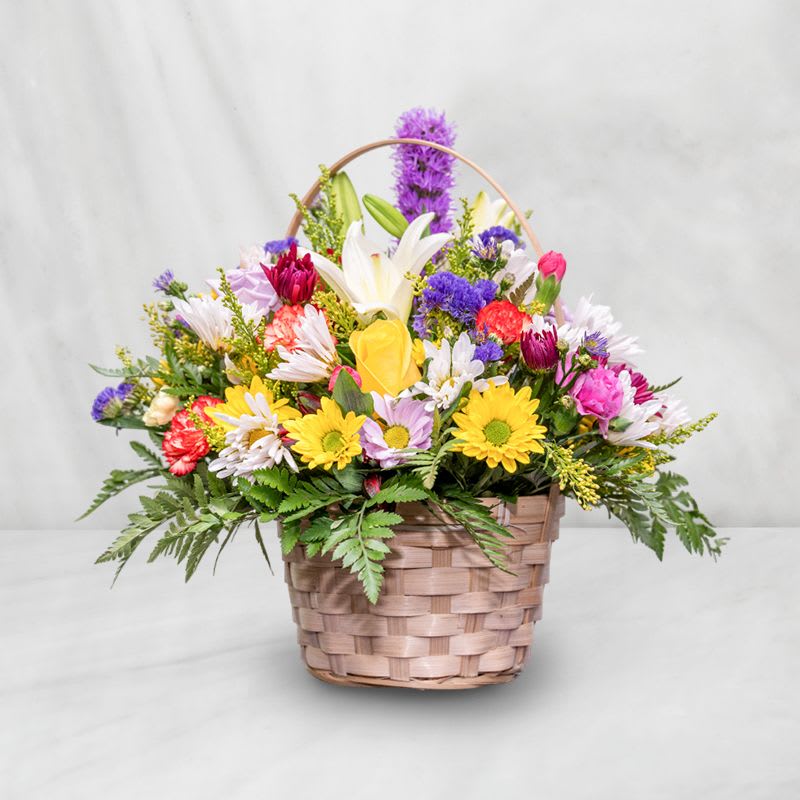 Mixed flower basket with daisies, lilies, and roses in a woven basket