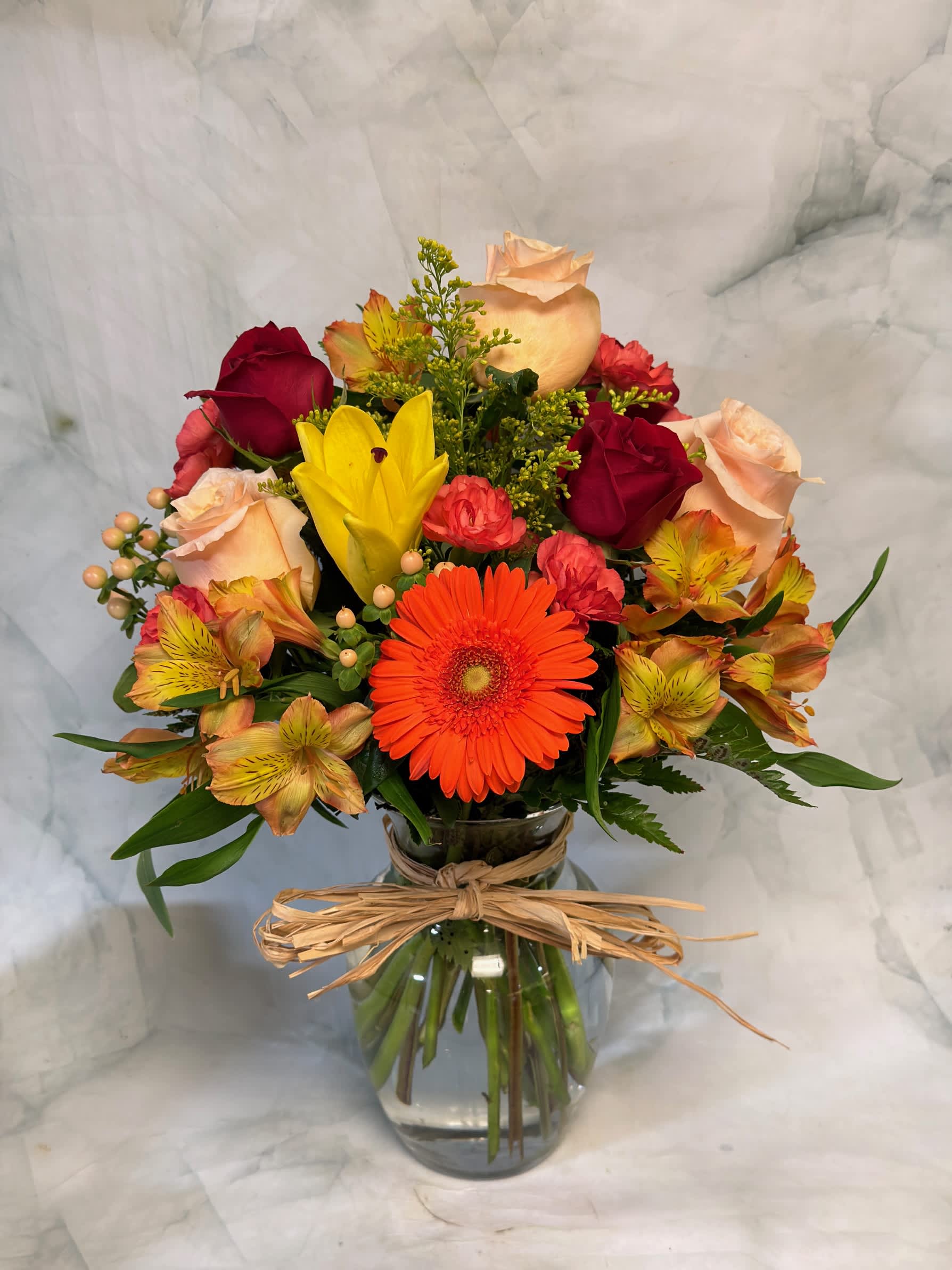Mixed bouquet of roses, gerbera daisies, and alstroemeria in a glass vase
