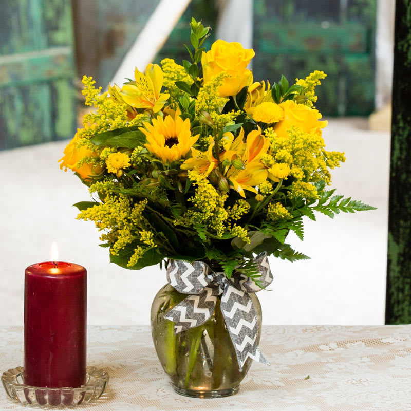 Yellow flower bouquet in a glass vase with a ribbon
