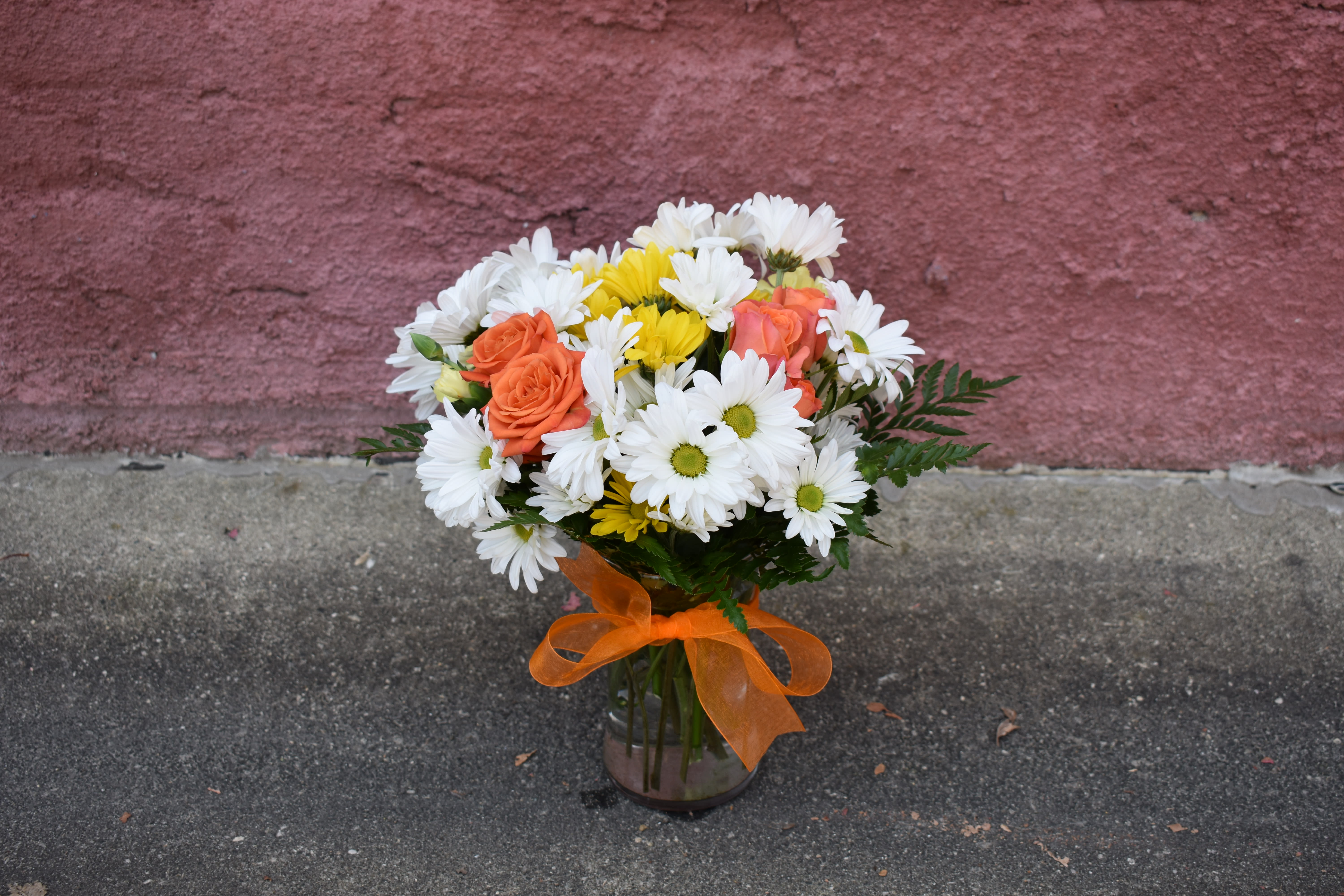 Sweet &amp; Splended Bouquet - This Bouquet radiates cheer and well-wishes with every sun-filled bloom! Orange spray roses, yellow and white traditional daisies and lush greens are brought together in a classic clear glass vase accented with a designer orange ribbon to create a bouquet set to brighten any day.
