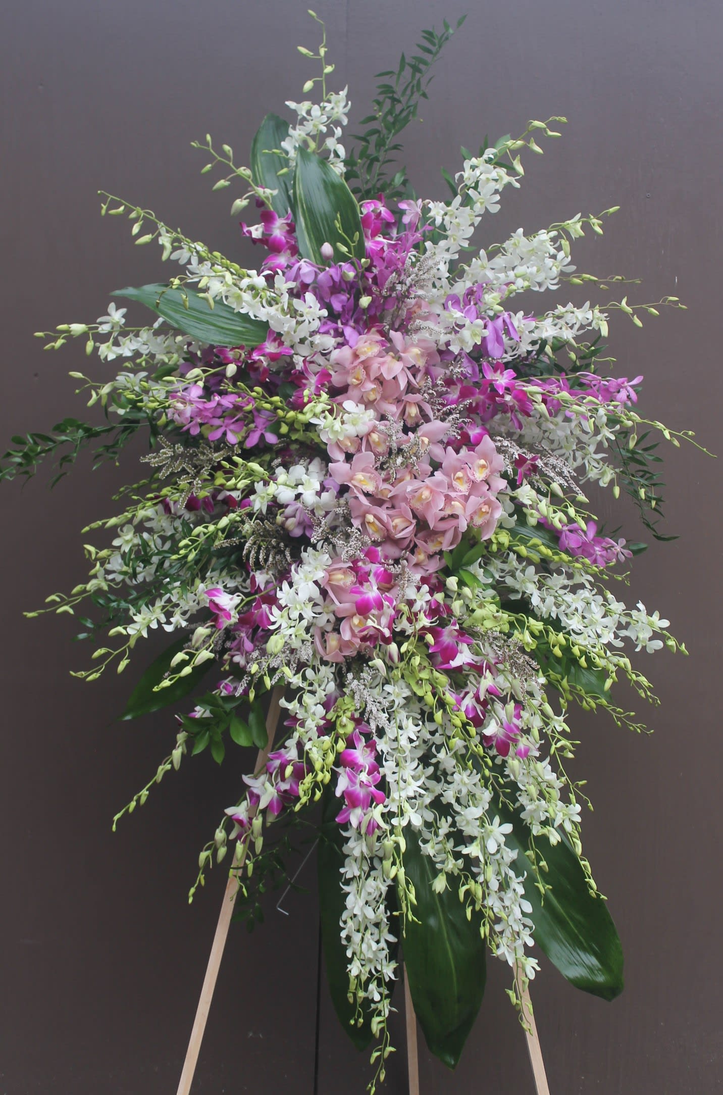 Tall standing arrangement of pink, white, and purple orchids