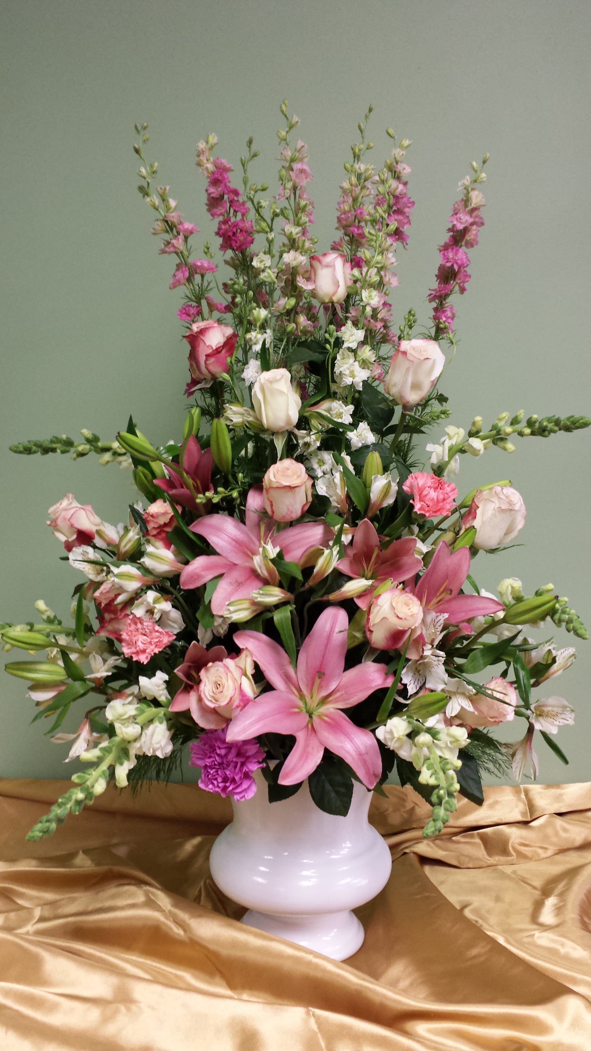 Pink lilies and roses arranged in a white vase