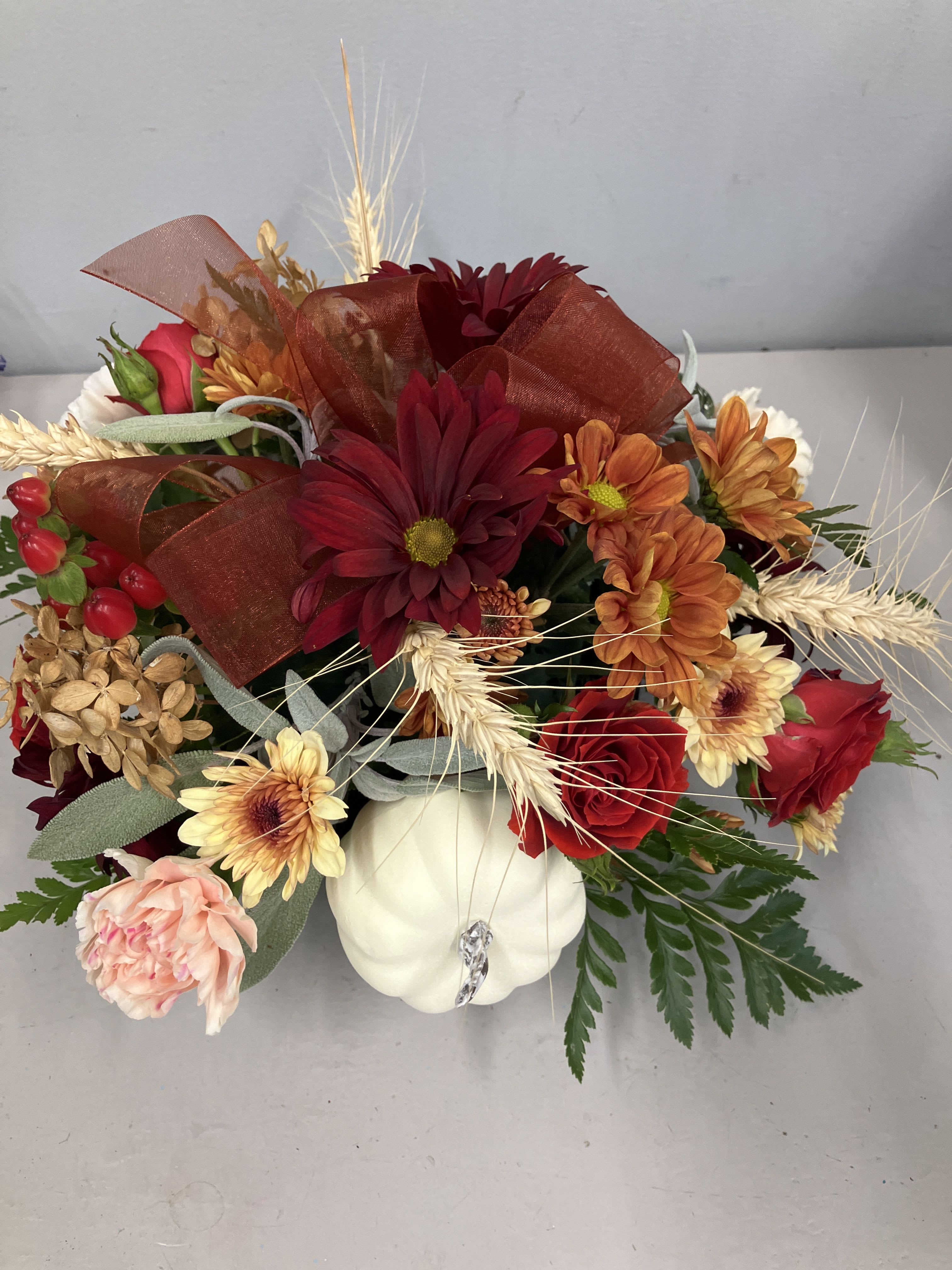 Autumn bouquet with chrysanthemums and roses in a white pumpkin container