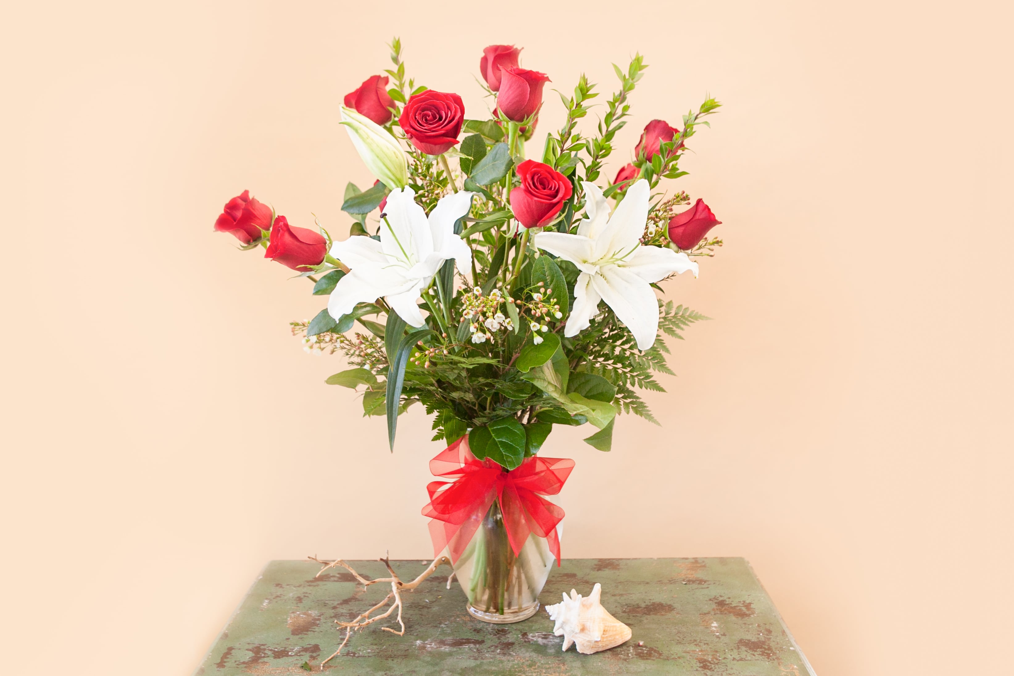 Red roses and white lilies in a clear vase with a red bow