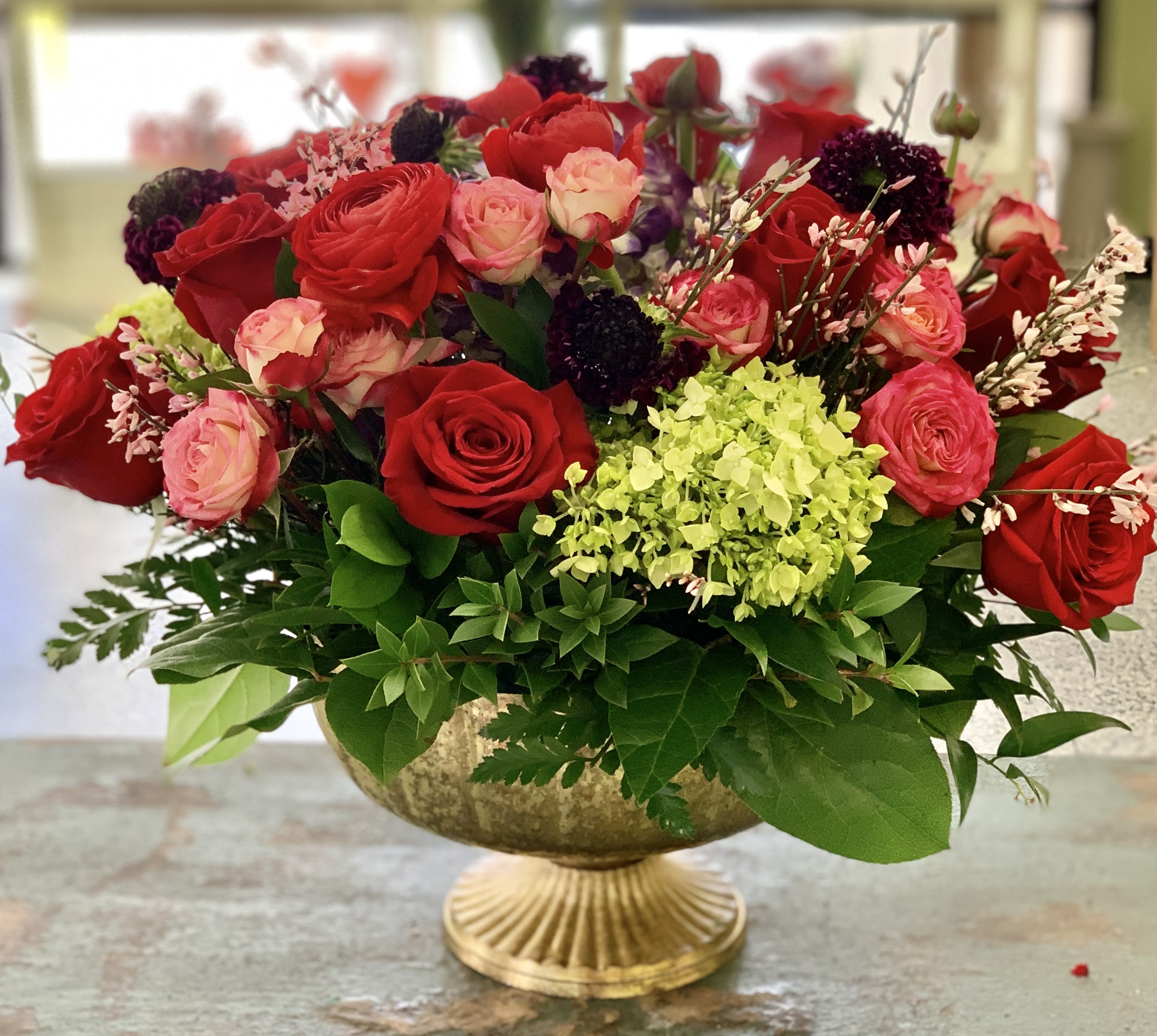Red and pink roses arranged in a gold pedestal bowl