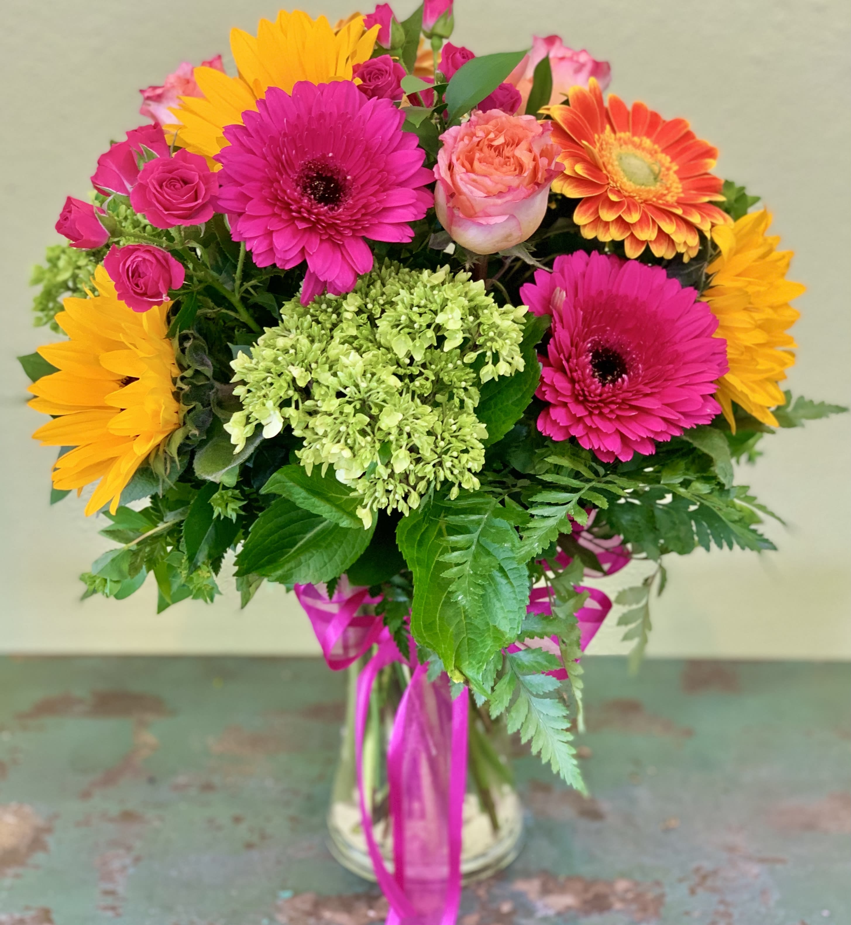 Bright mixed bouquet in a glass vase with pink, orange, and yellow blooms