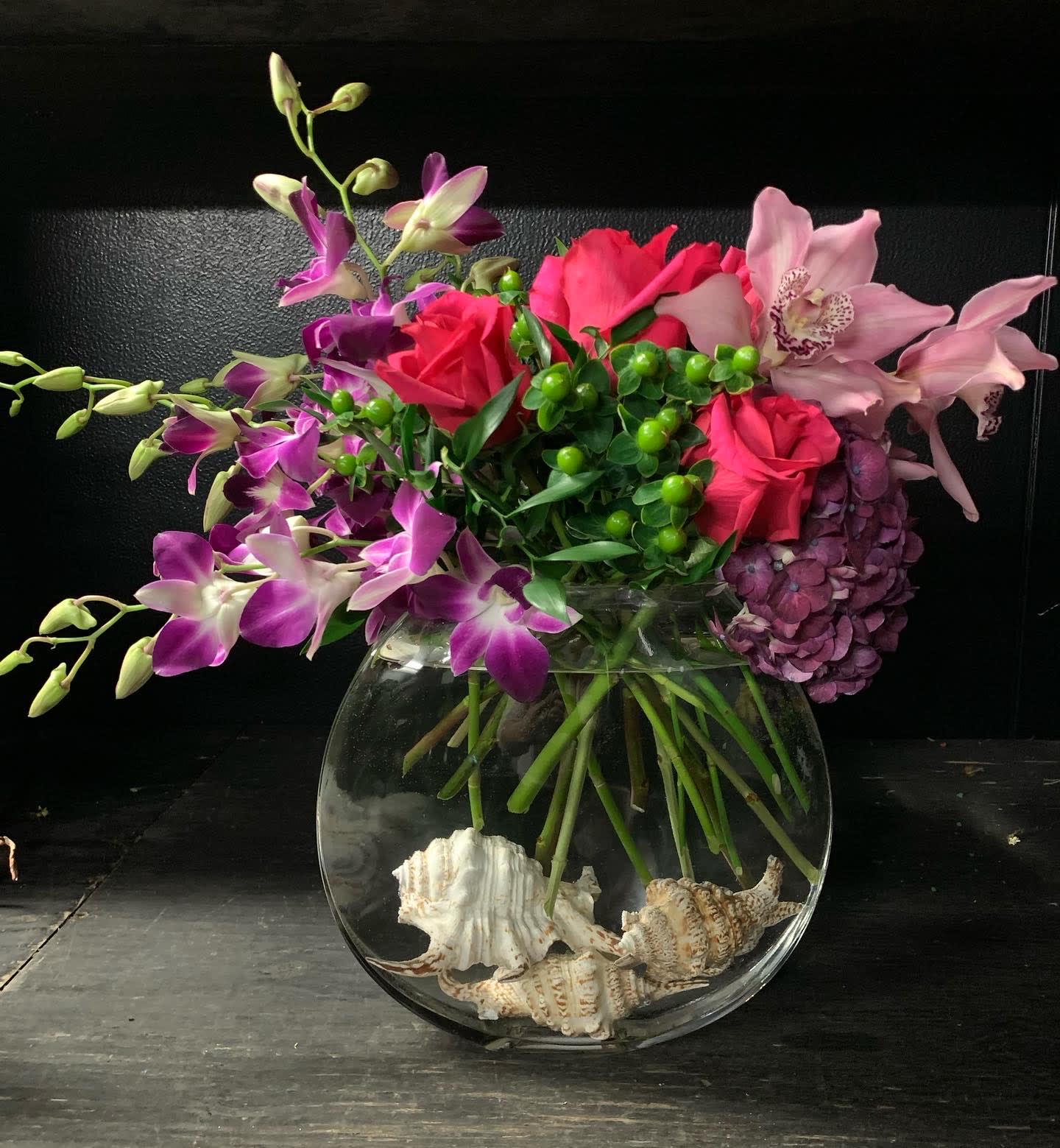Bouquet of pink roses and purple orchids in a glass bowl vase