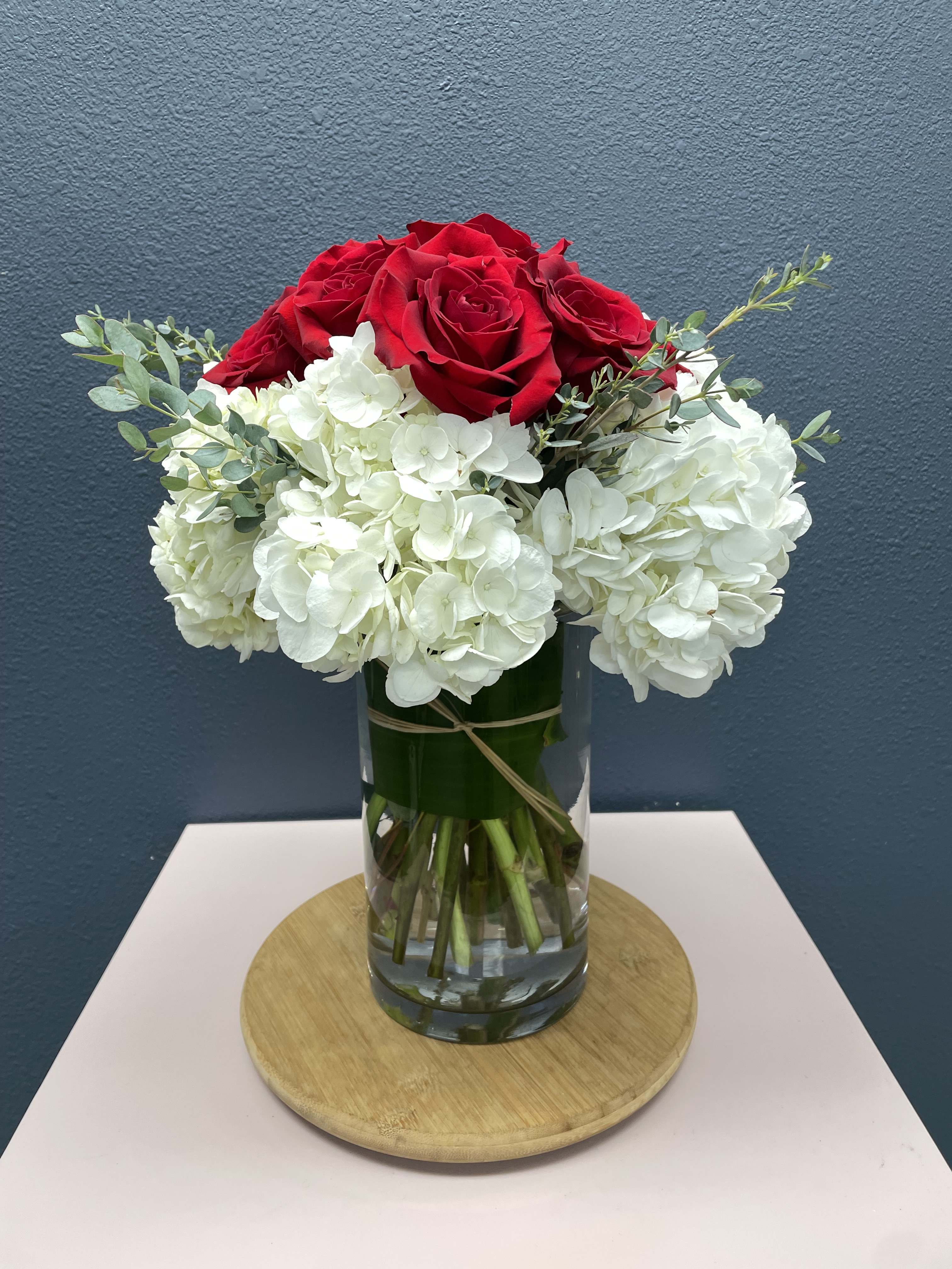 Red roses and white hydrangeas in a clear glass vase