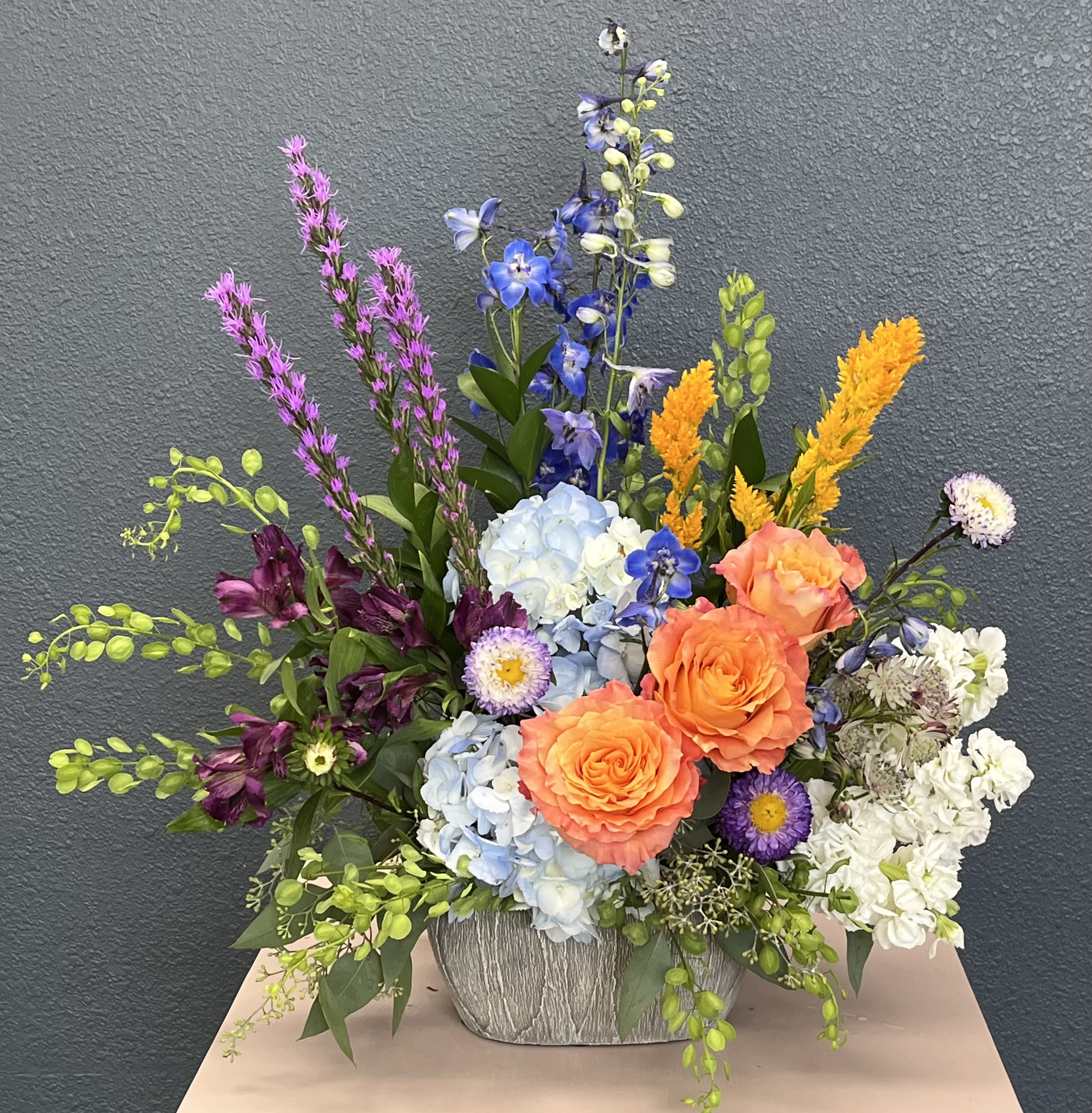 Colorful mixed flower arrangement in a textured gray container