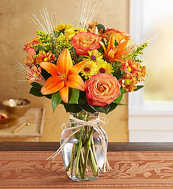 Bouquet of orange and pink flowers in a clear glass vase with a ribbon