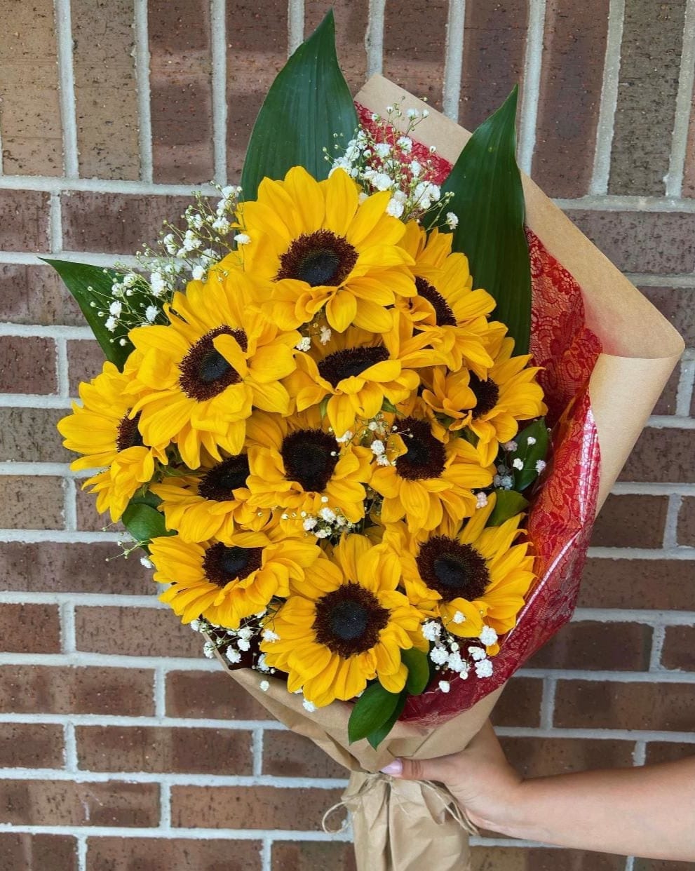 Bouquet of yellow sunflowers with baby's breath in brown paper