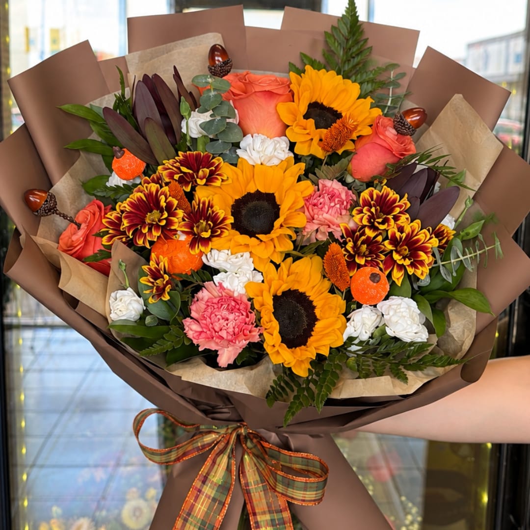 Bouquet of sunflowers, roses, carnations, and chrysanthemums wrapped in brown paper