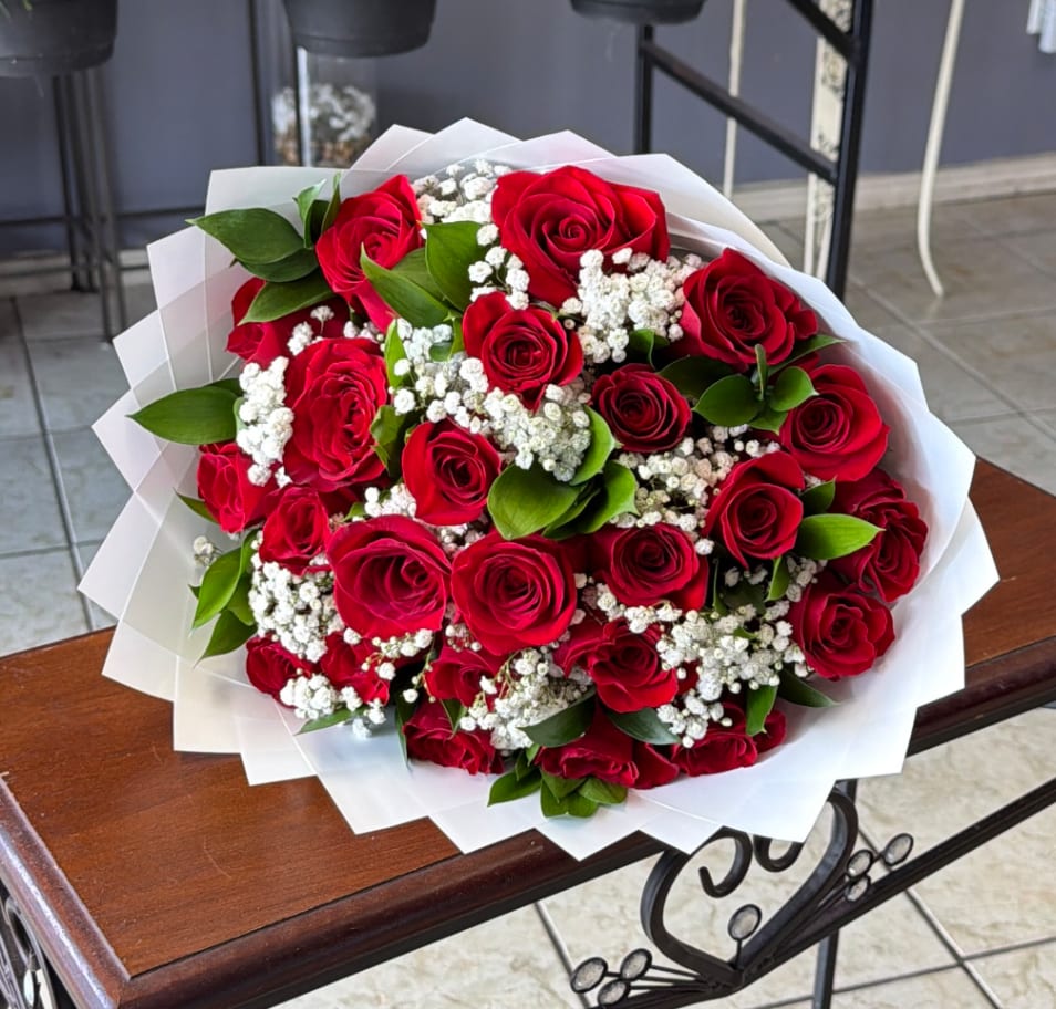 Bouquet of red roses with white baby's breath wrapped in white paper