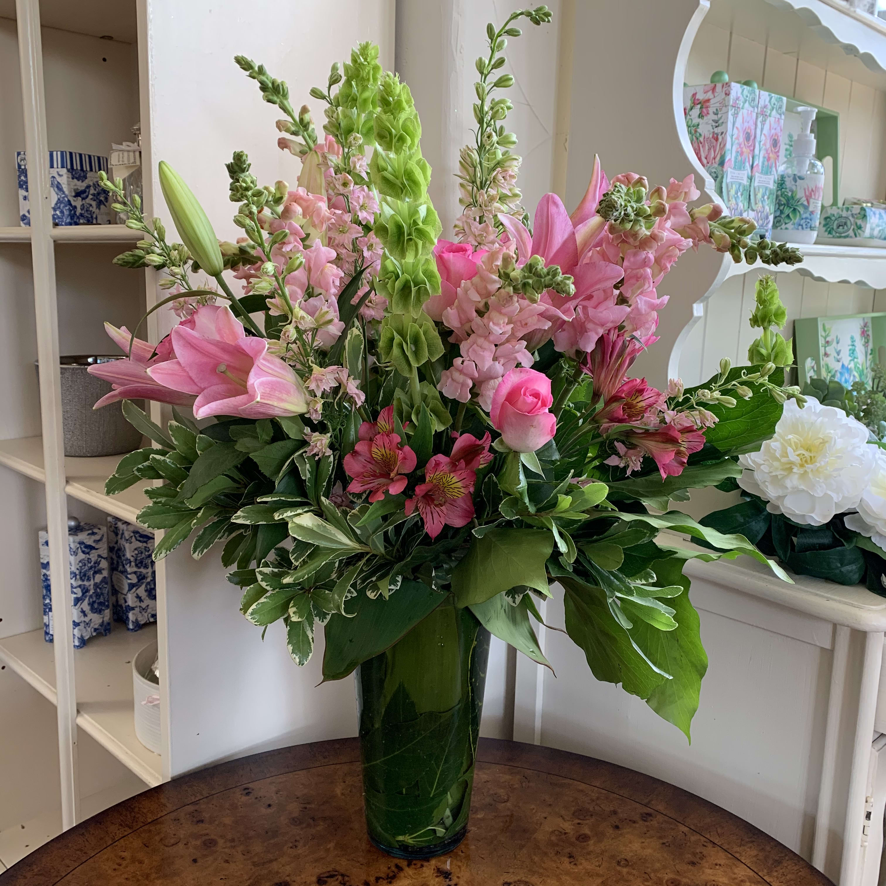 Pink lilies and snapdragons in a tall green vase