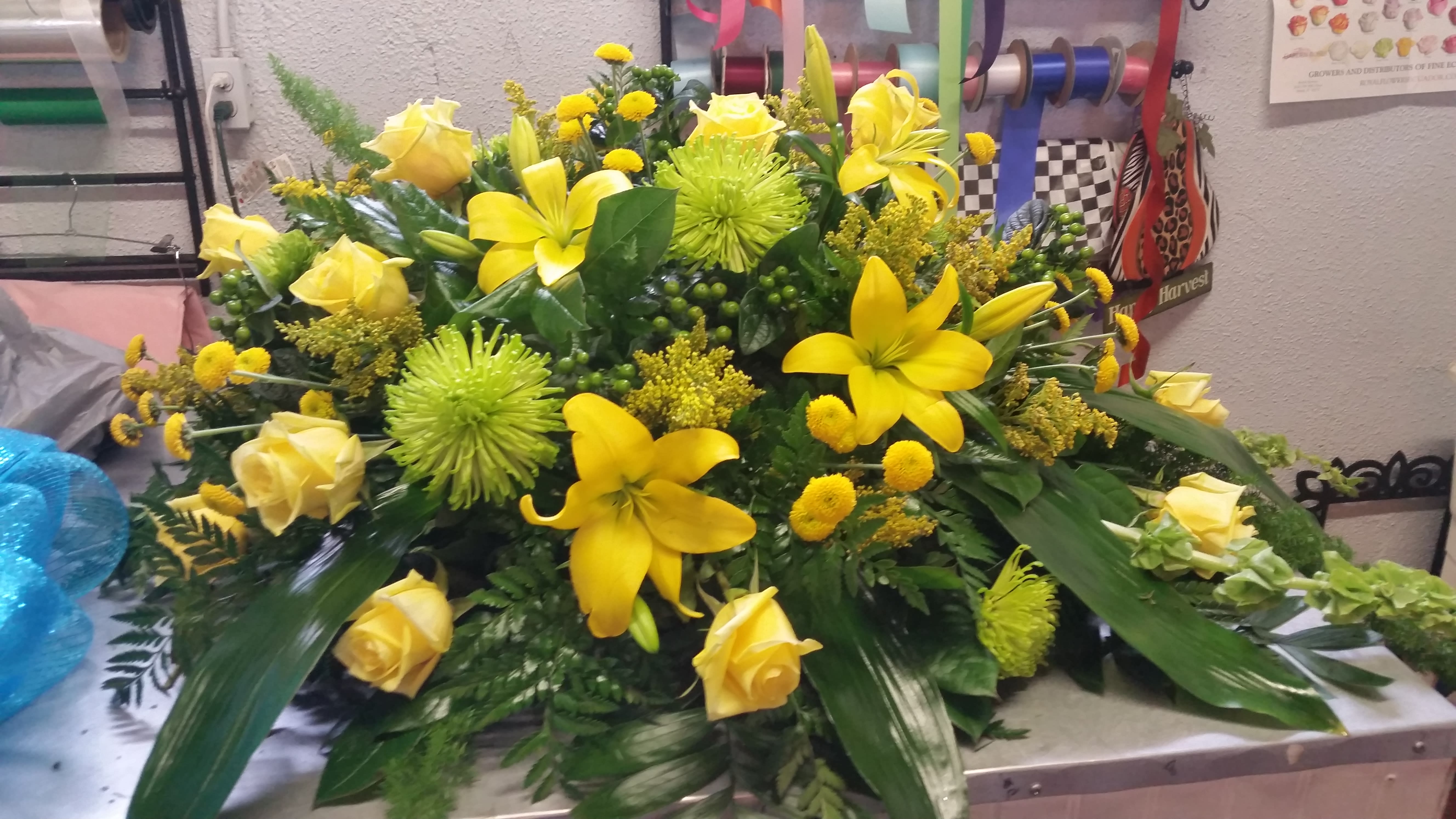 Yellow roses and lilies arranged in a low, wide floral display