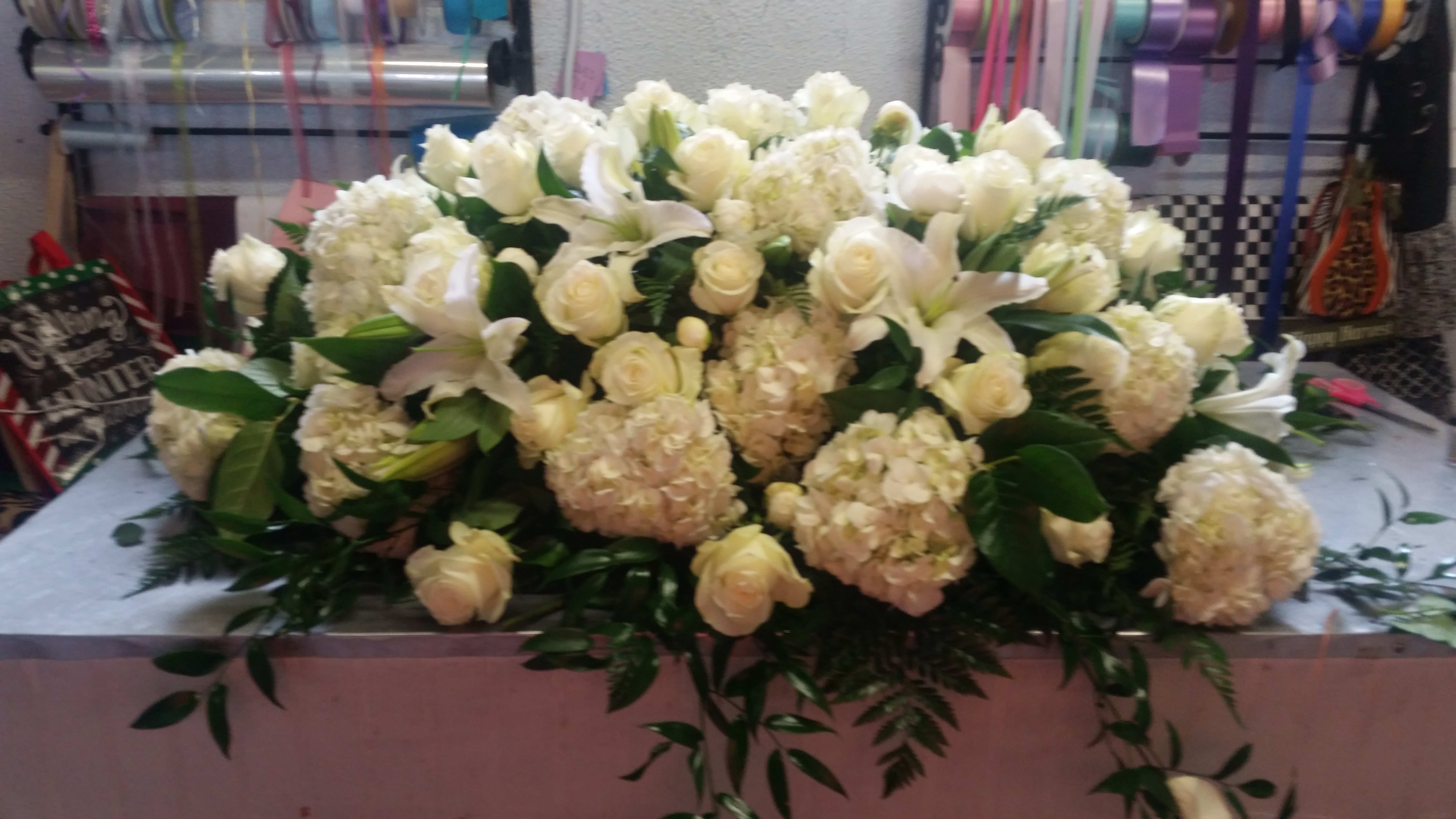 Large white floral arrangement with roses, lilies, and hydrangeas
