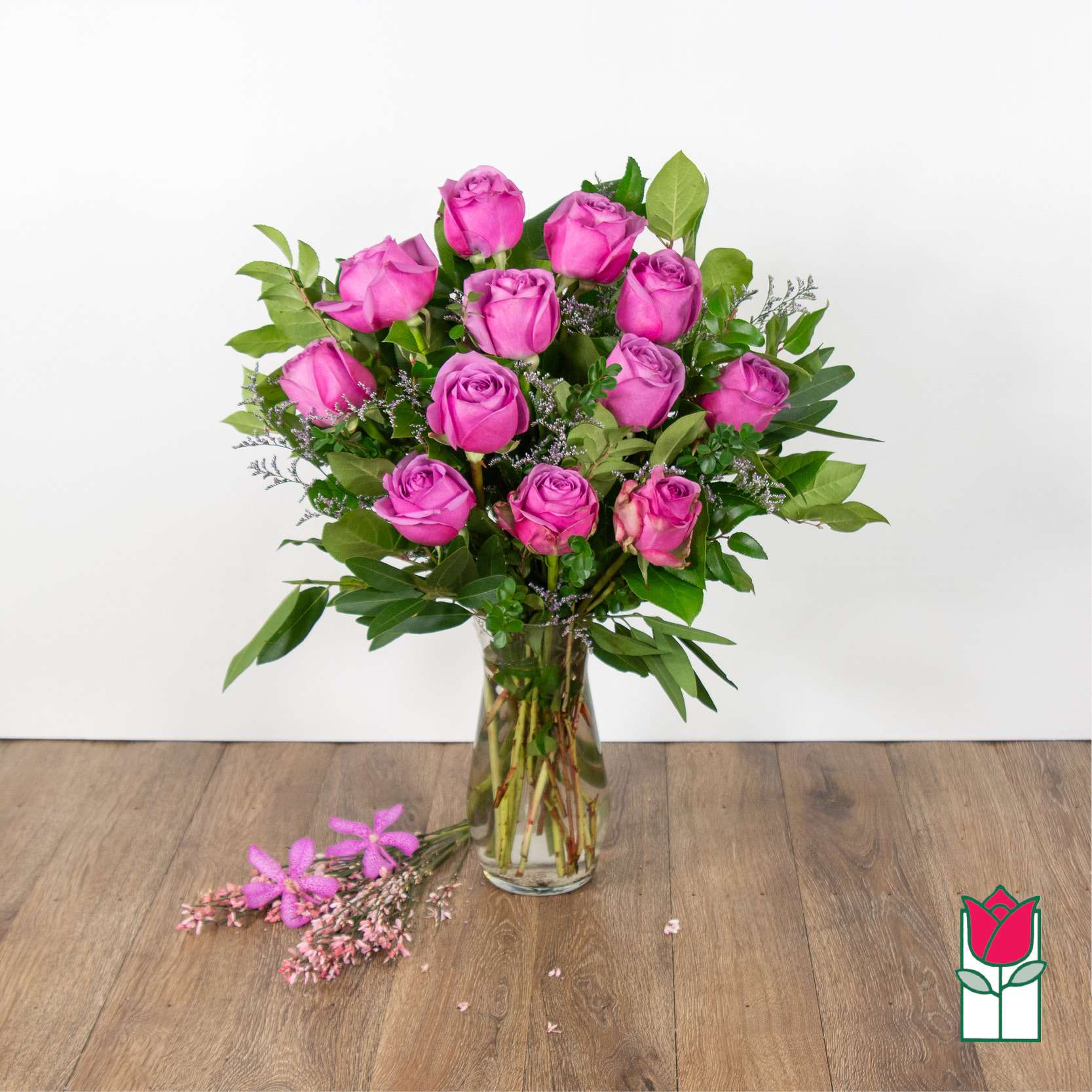 Pink roses arranged in a clear glass vase with greenery