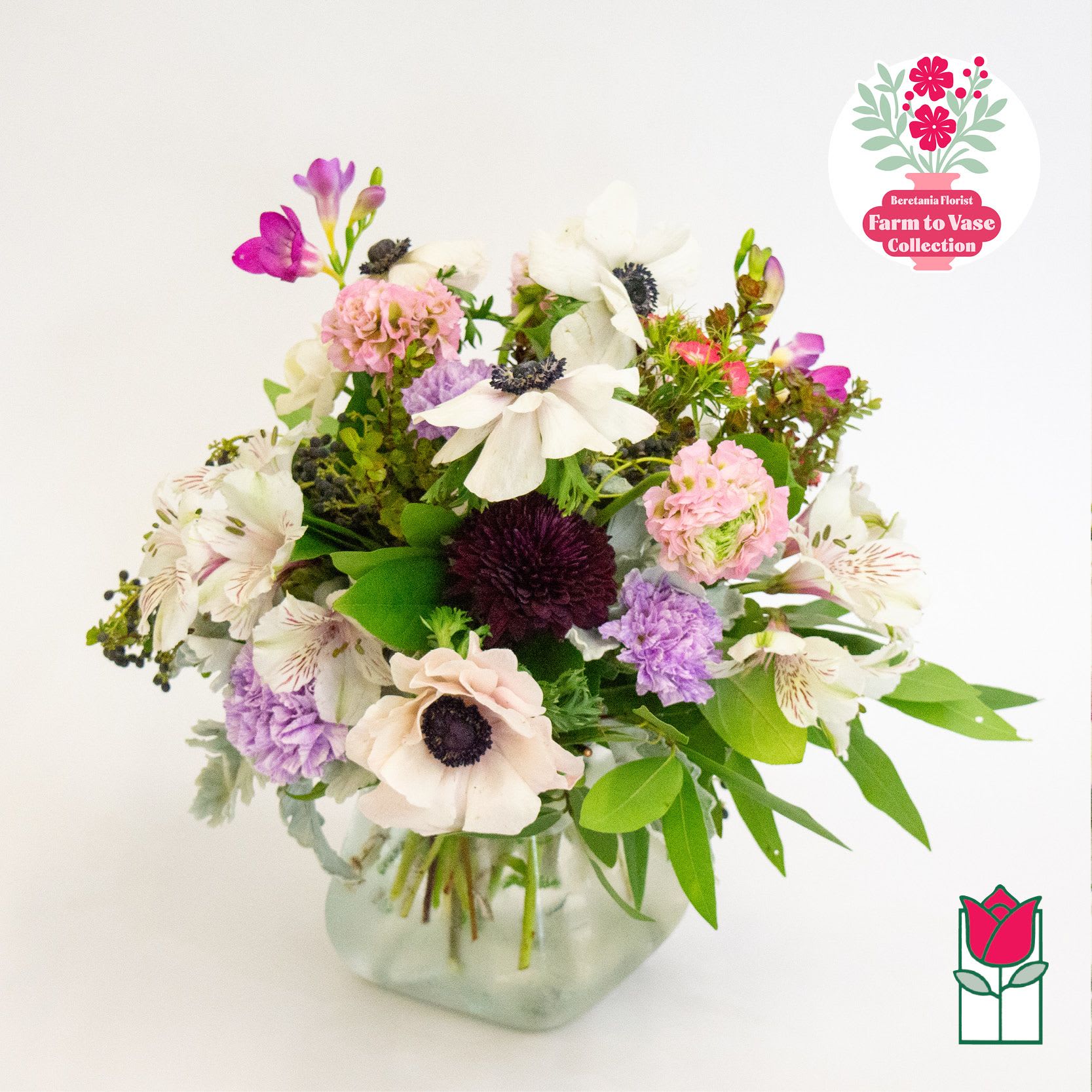 Mixed bouquet of white, pink, and purple flowers in a glass vase