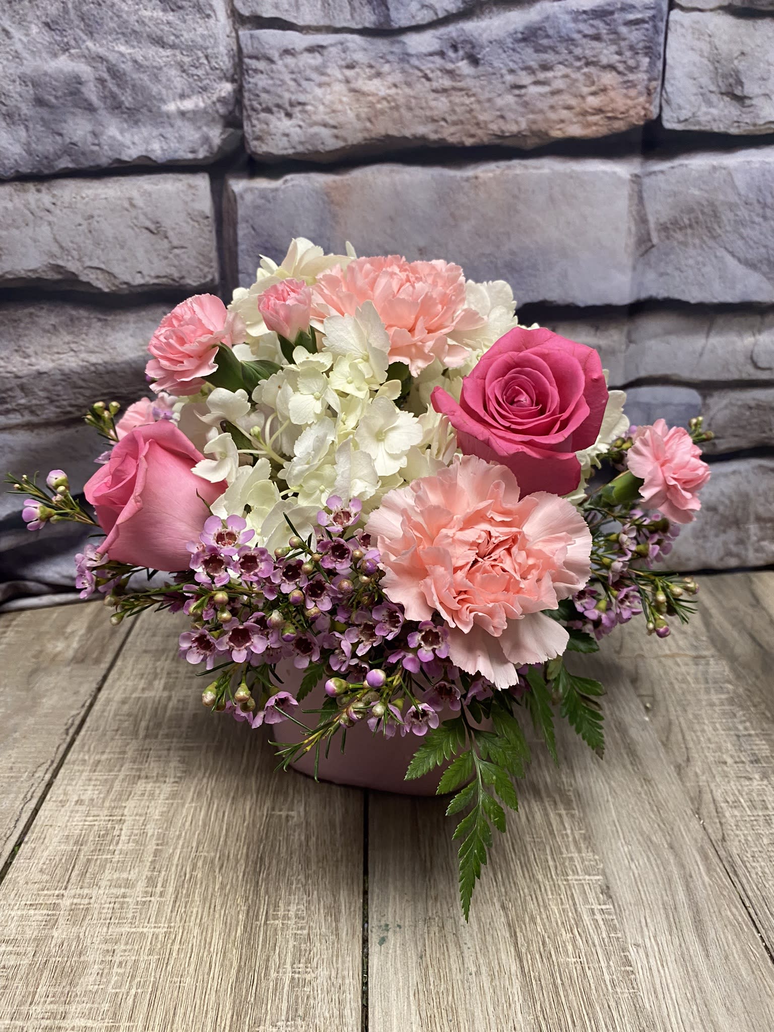 Pink and white floral arrangement in a low container