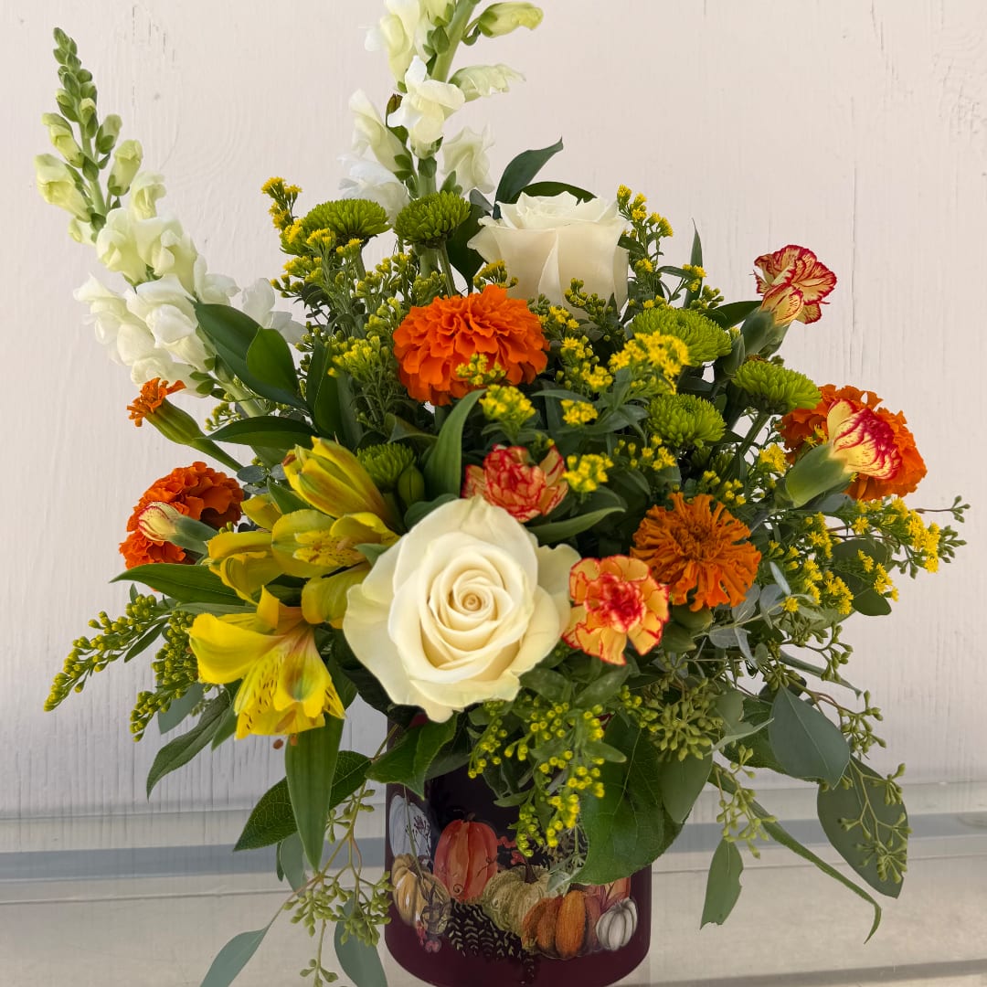 Mixed bouquet with white roses, yellow lilies, and orange flowers in a decorated vase
