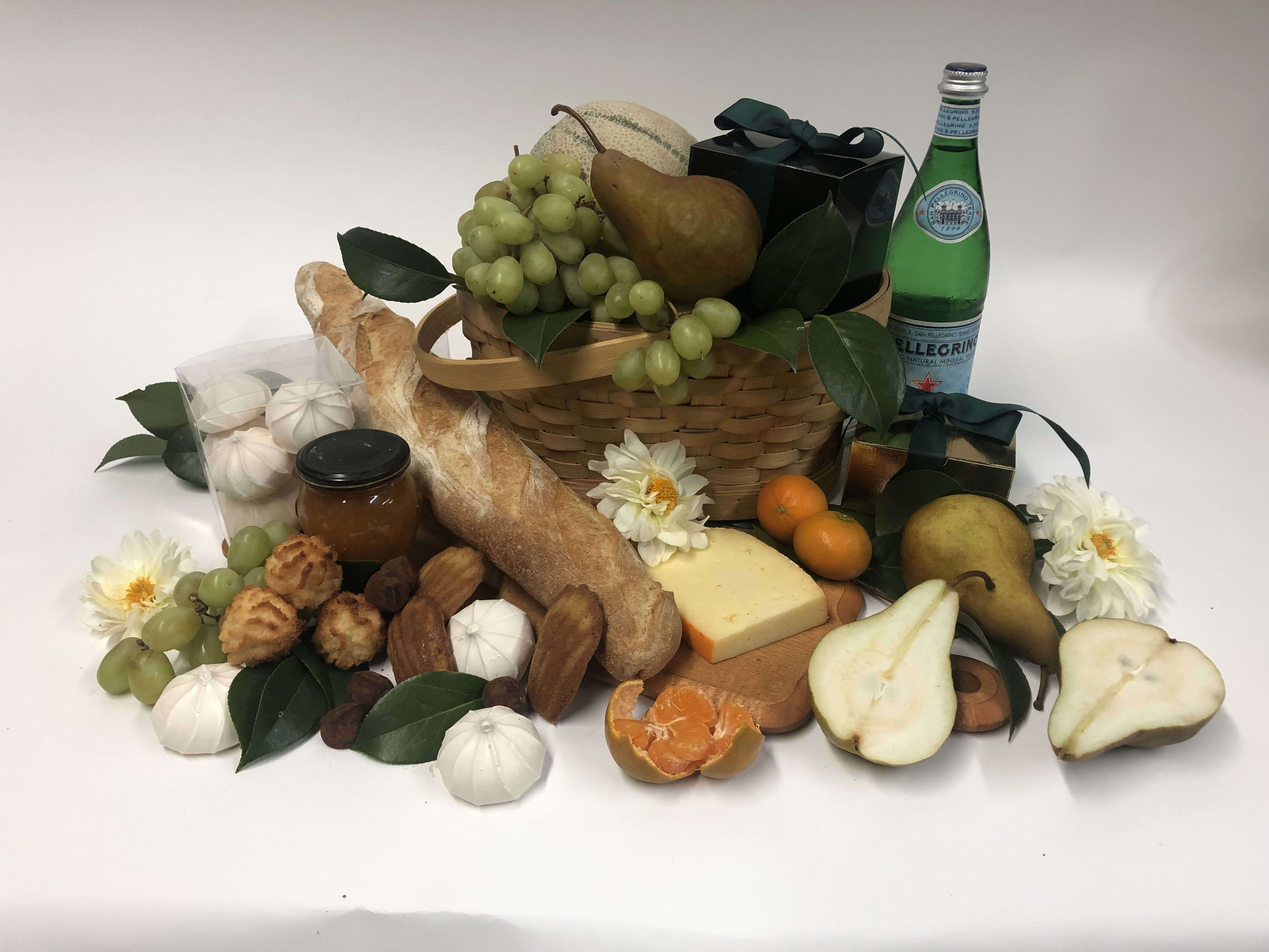 Gift basket with fruit, bread, cheese, pastries, and a bottle of sparkling water