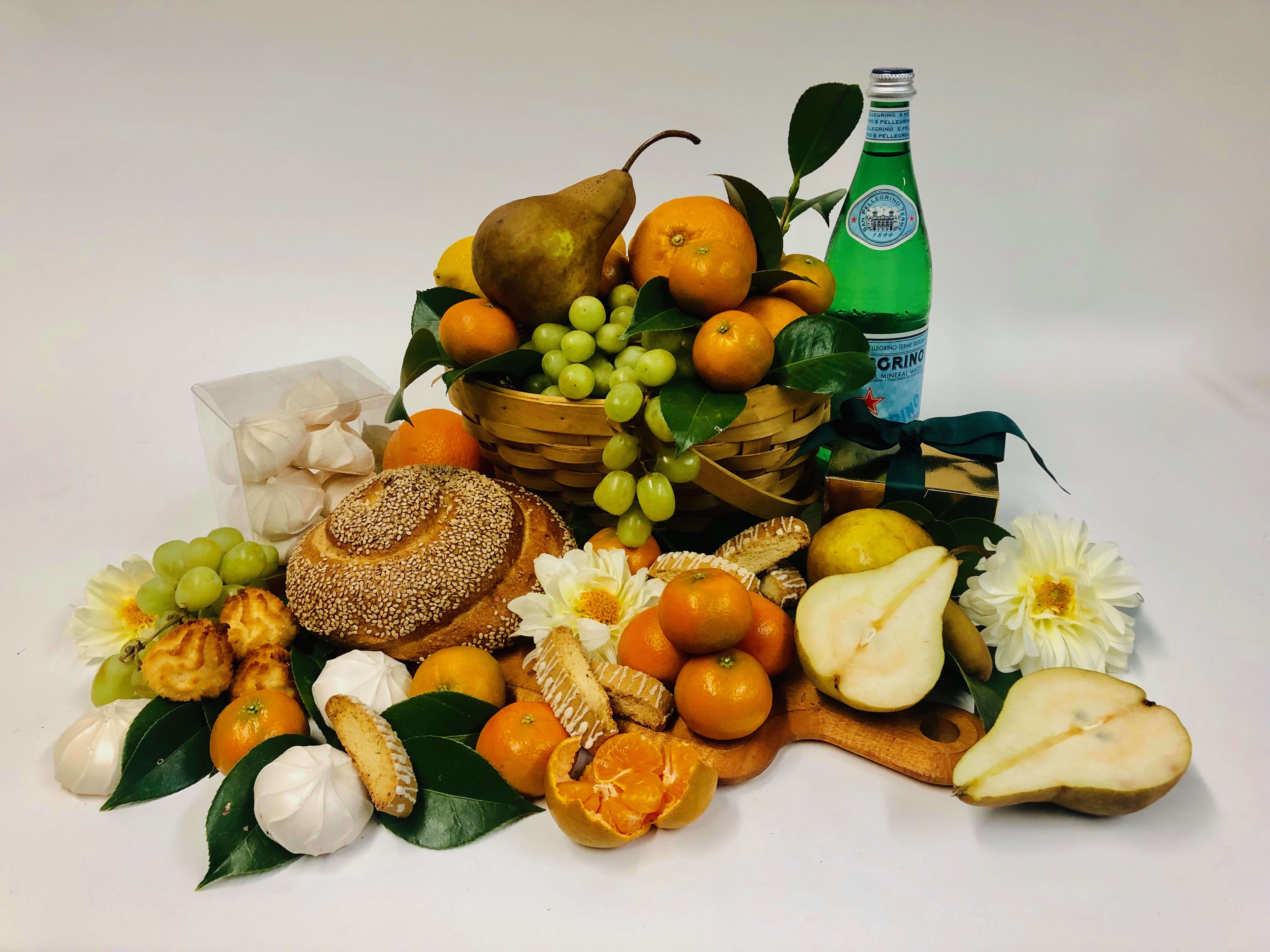 Fruit and bread gift basket with flowers and a green bottle