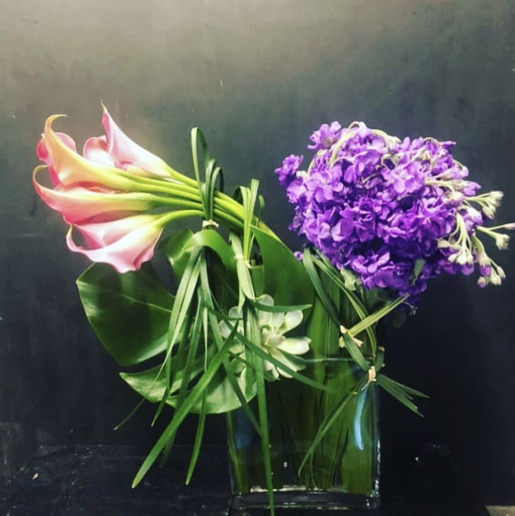 Bouquet of pink calla lilies and purple flowers in a glass vase