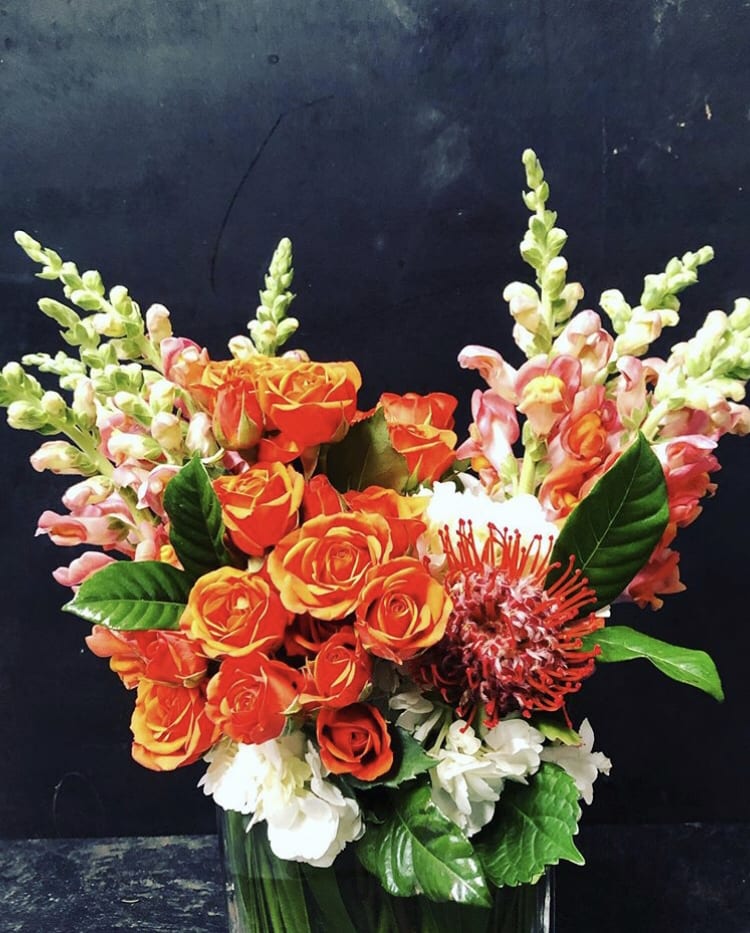 Orange roses with pink snapdragons in a glass vase
