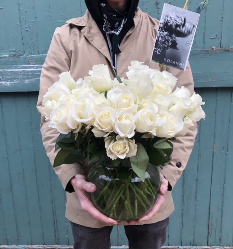 Person holding a vase of white roses