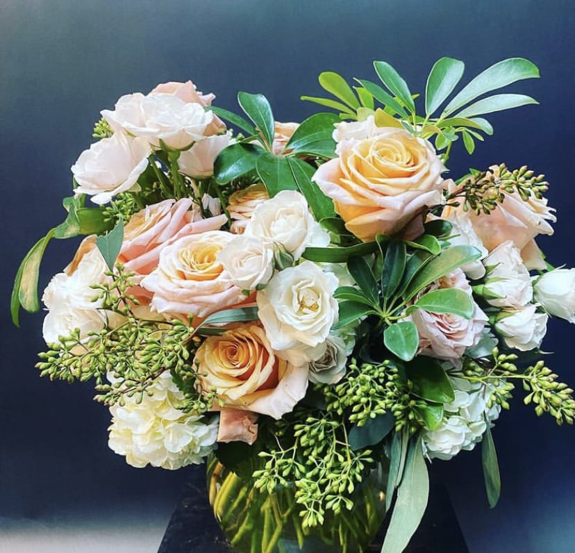 Peach and white roses arranged in a glass vase
