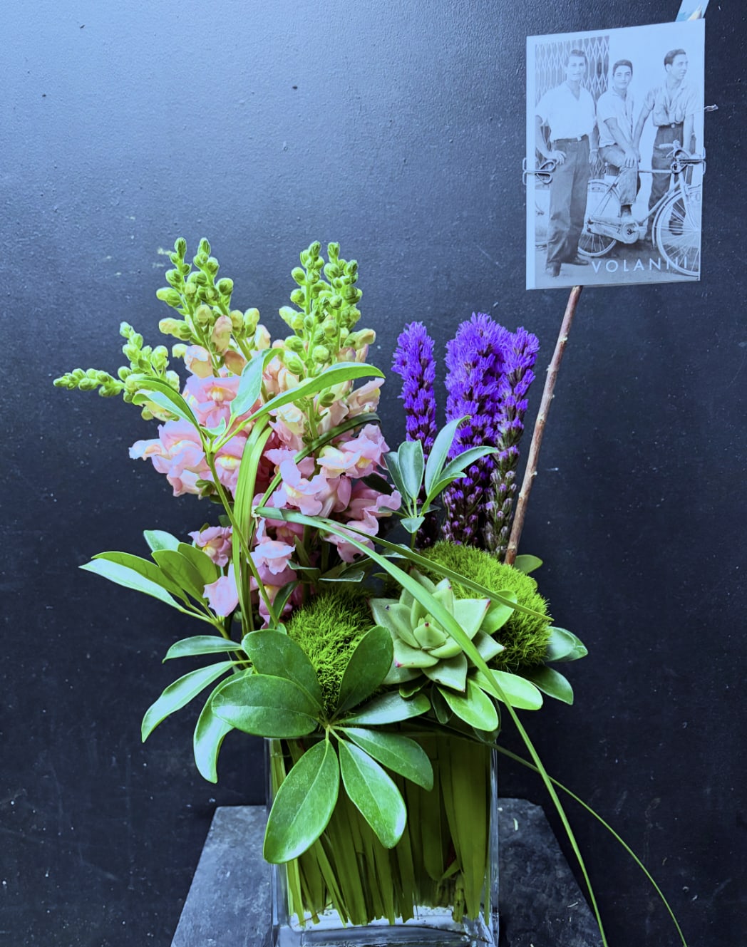 Pink snapdragons and purple flowers in a glass vase with succulents