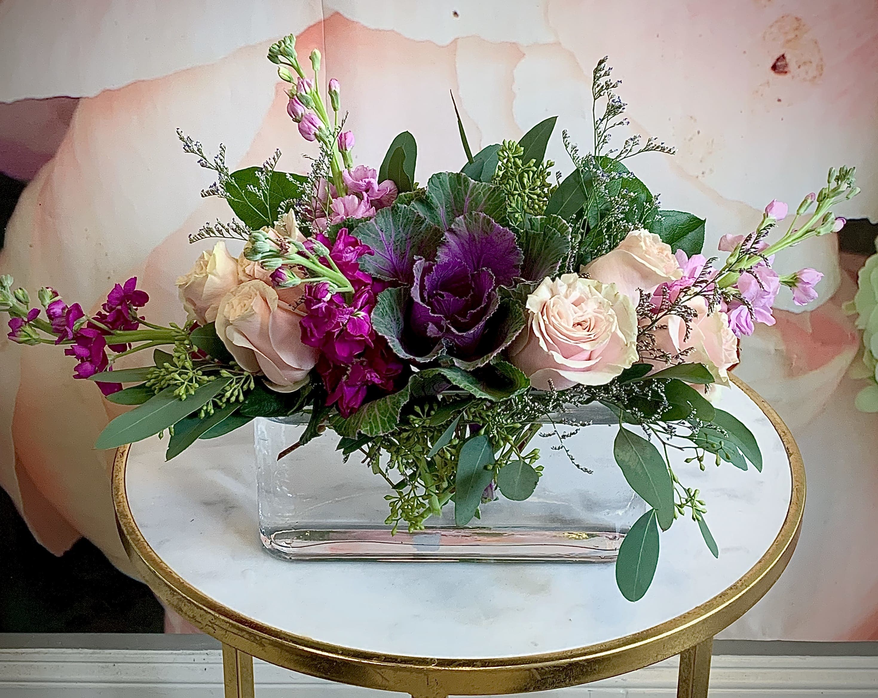 Pink and purple floral arrangement in a clear rectangular vase