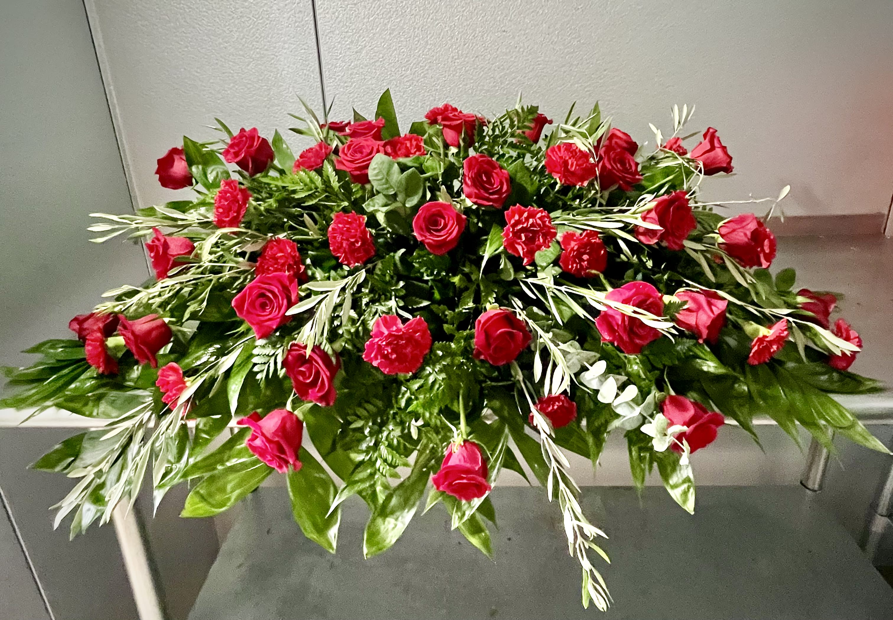 Red Rose Casket Spray - A classic casket spray with an abundance of red roses and red carnations will express your love and devotion with beauty.