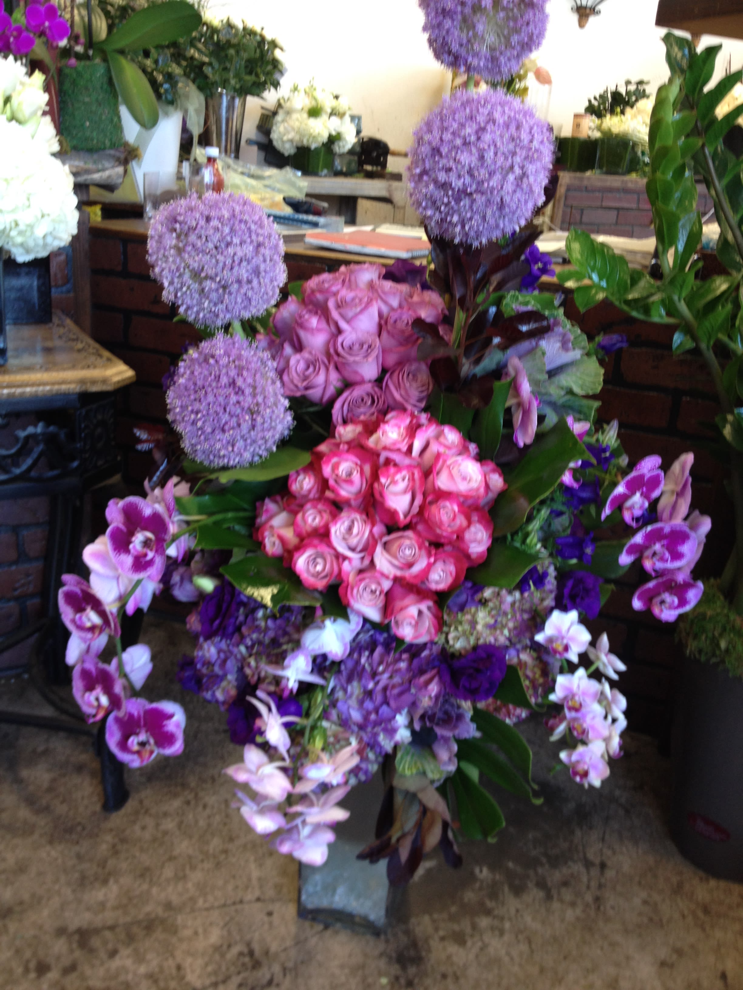 Tall floral arrangement with pink roses, purple allium, and orchids