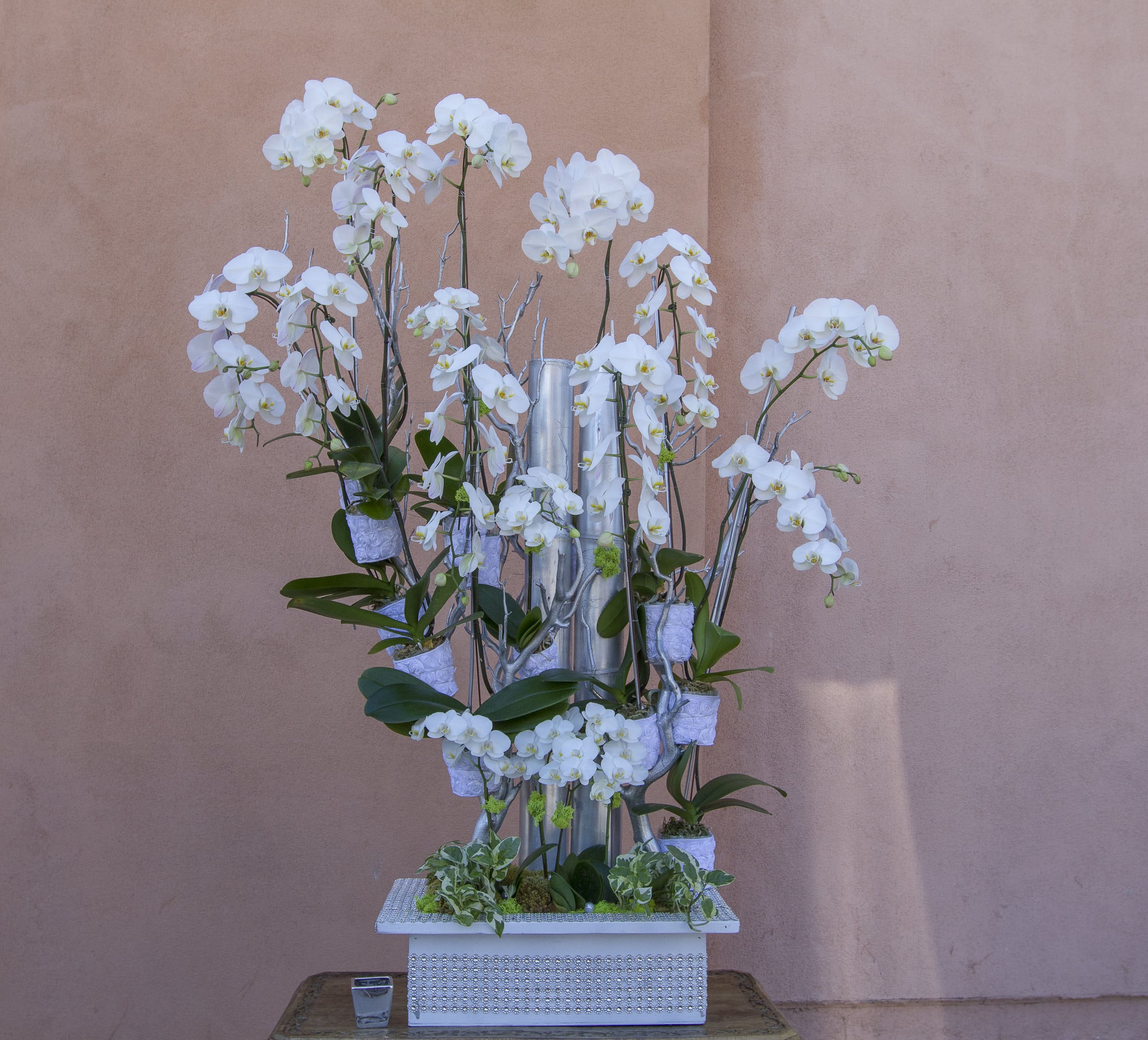 Tall white orchid arrangement in a decorative silver vase