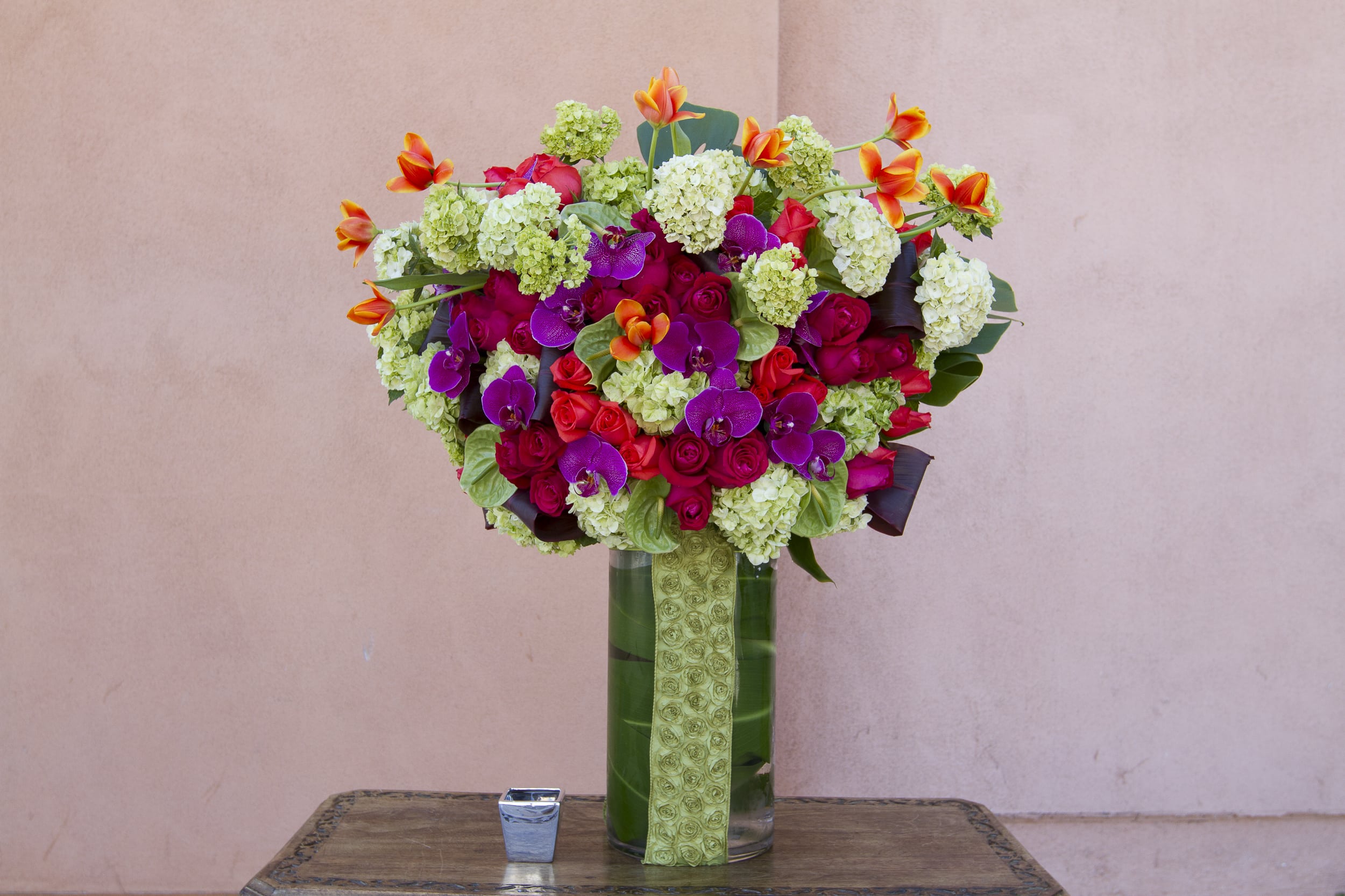 Bright mixed bouquet in a tall glass vase with pink, purple, and orange flowers.