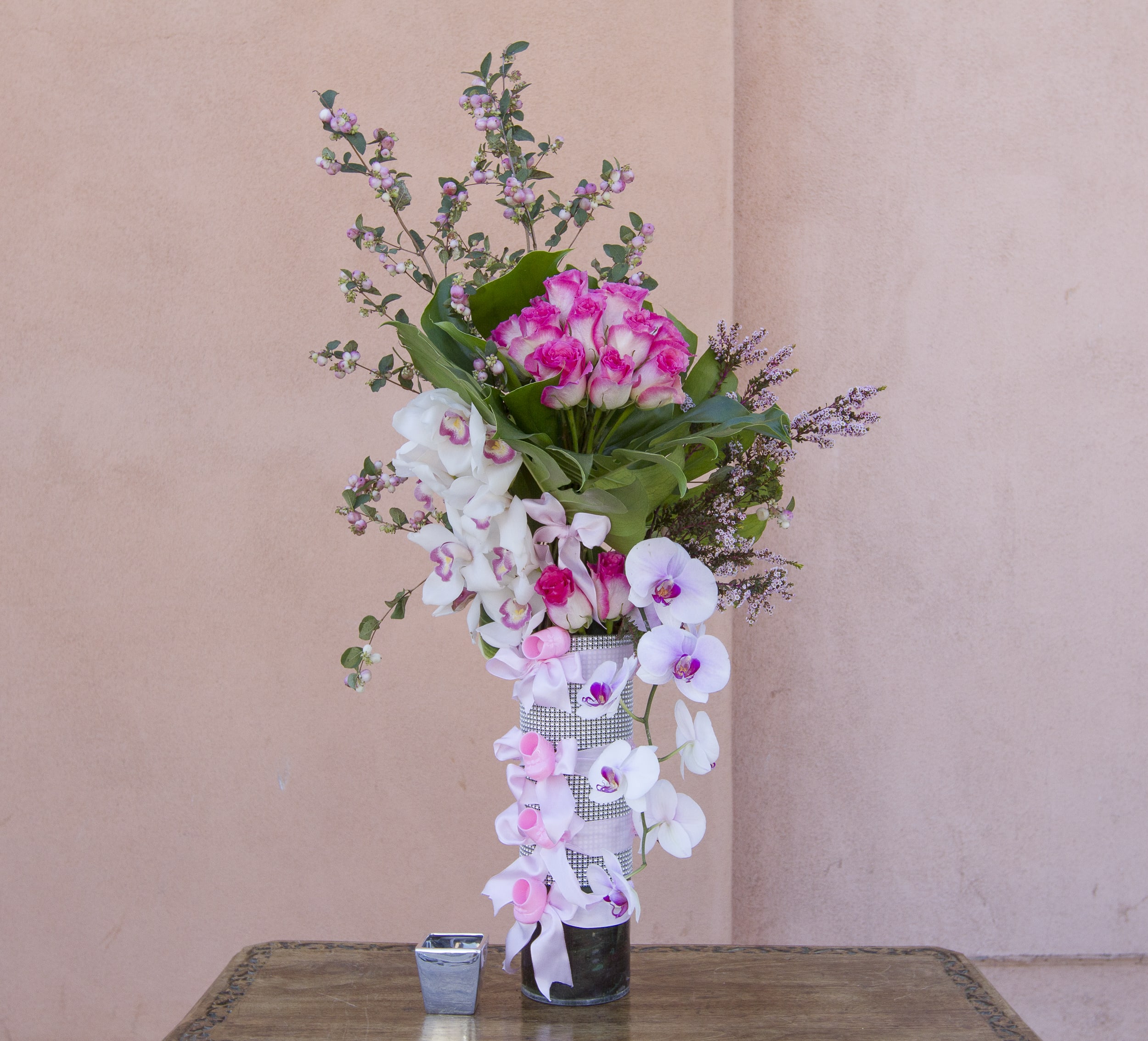 Tall pink and white orchid arrangement in a glass vase