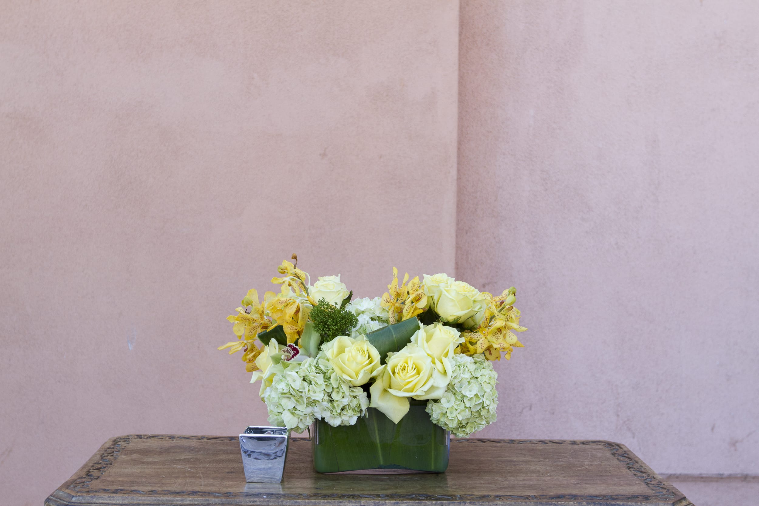 Yellow roses and pale hydrangeas arranged in a green vase
