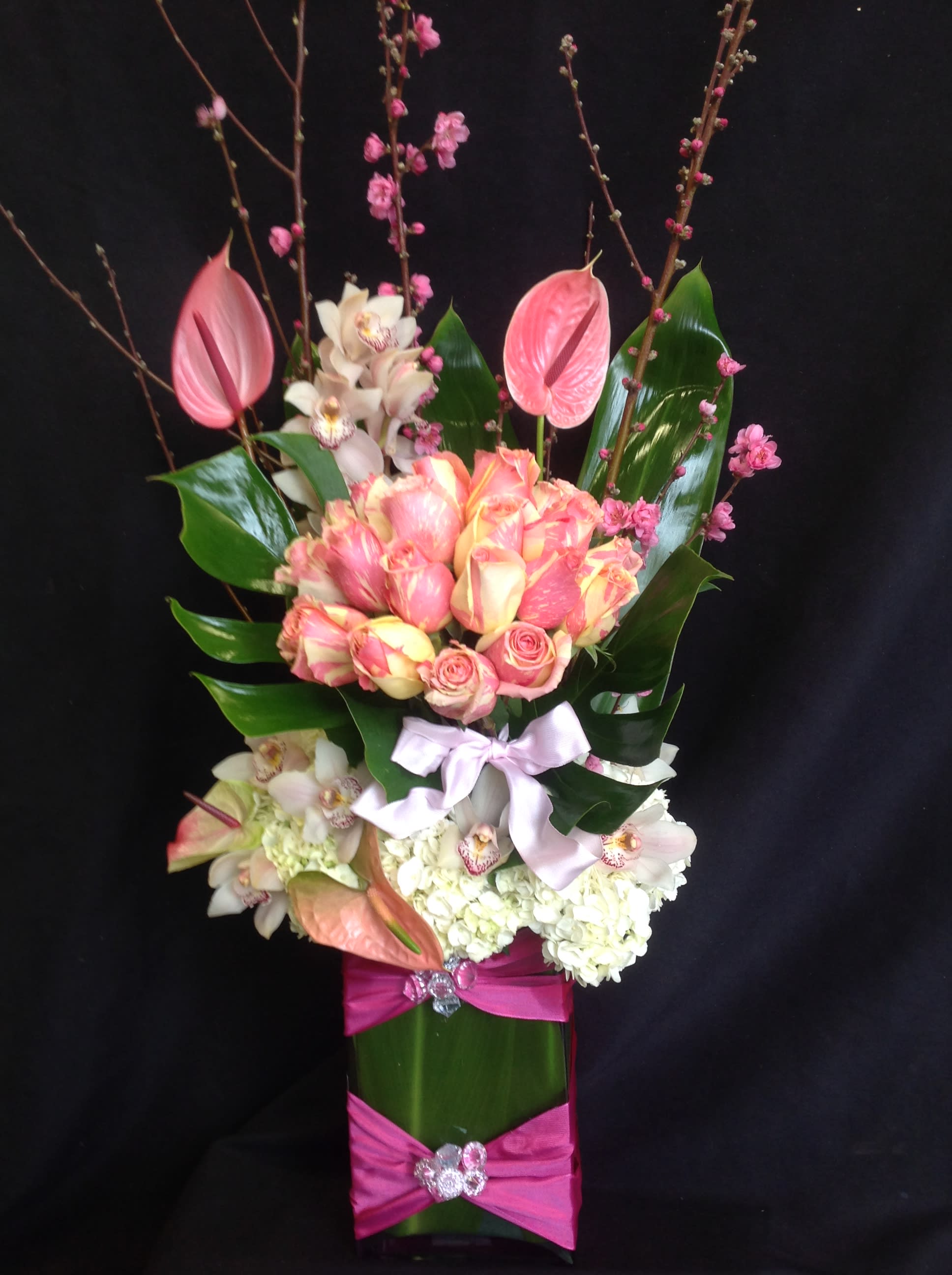 Tall bouquet of pink and white flowers with a ribbon-wrapped vase