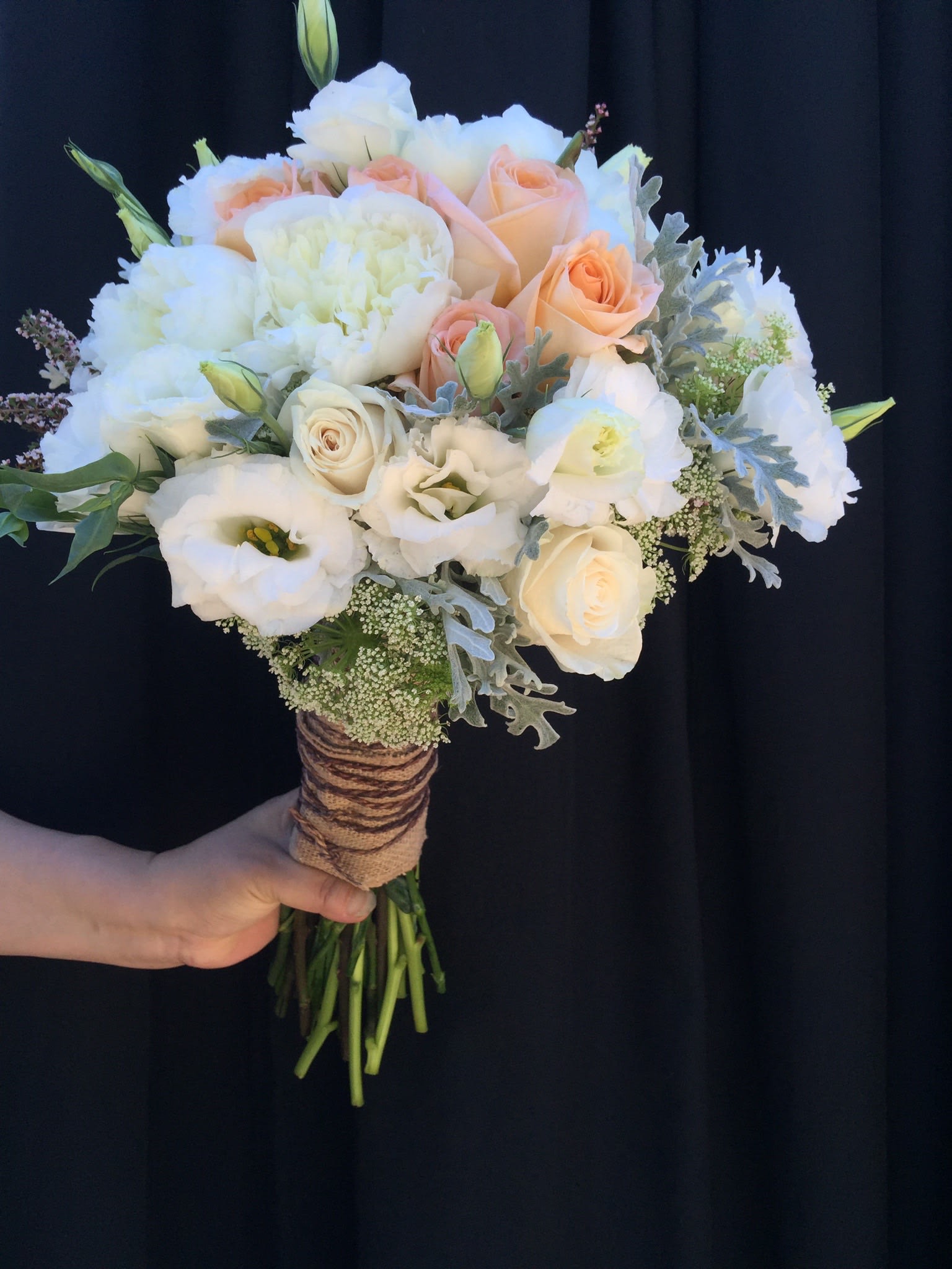 Handheld bouquet of white and peach roses with white blooms