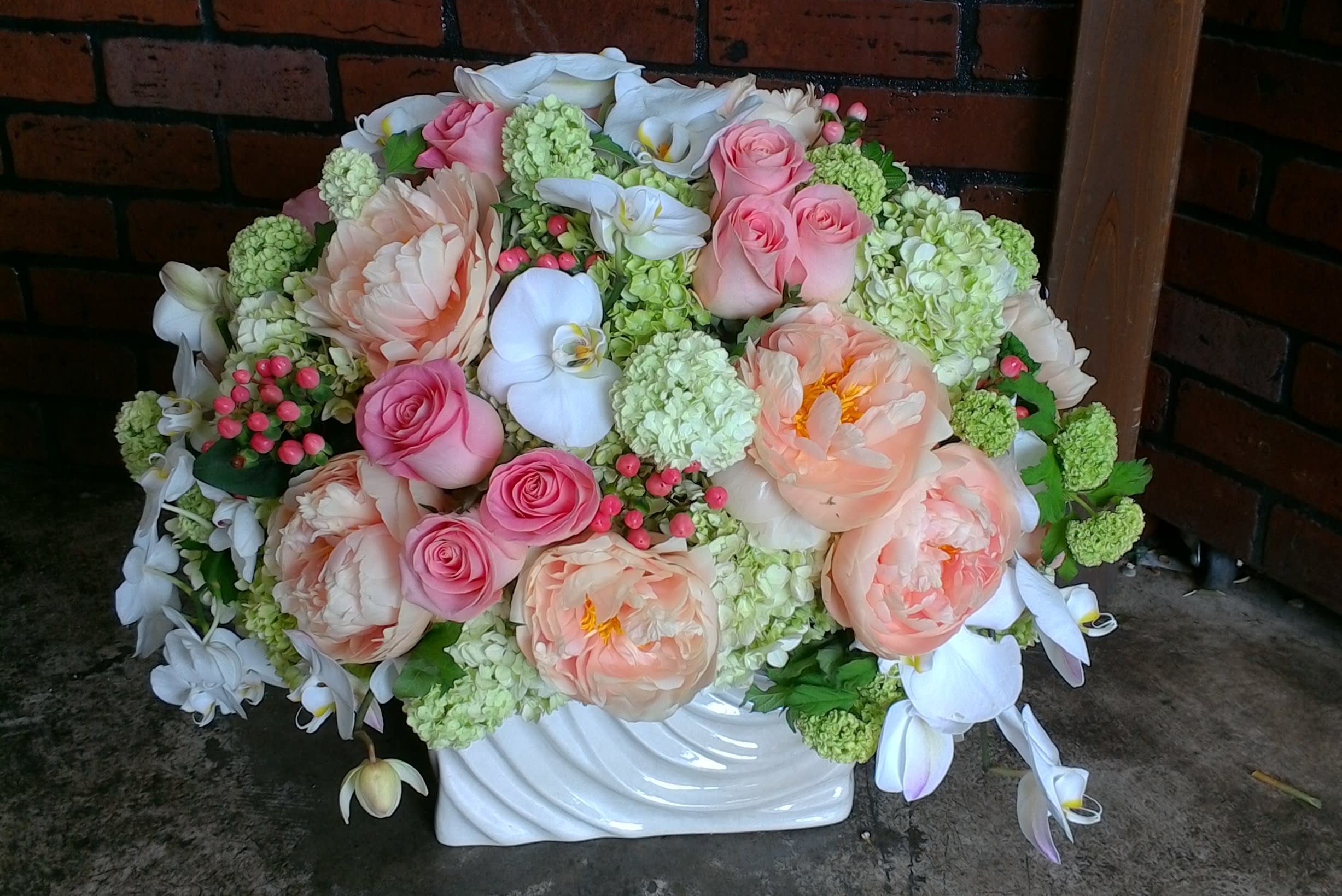 Large pastel floral arrangement in a white vase with pink and white blooms