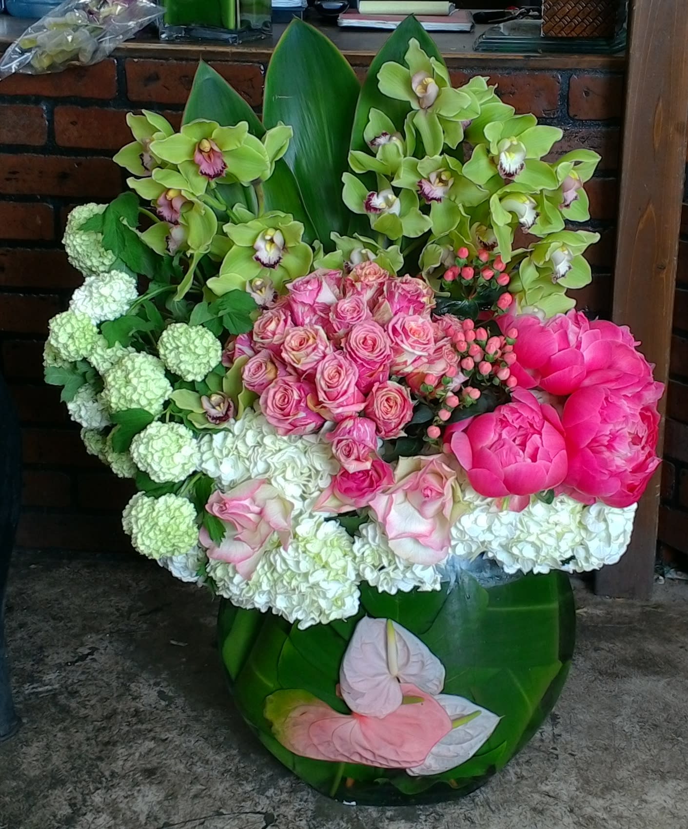 Bouquet of pink roses, green orchids, and white hydrangeas in a green vase