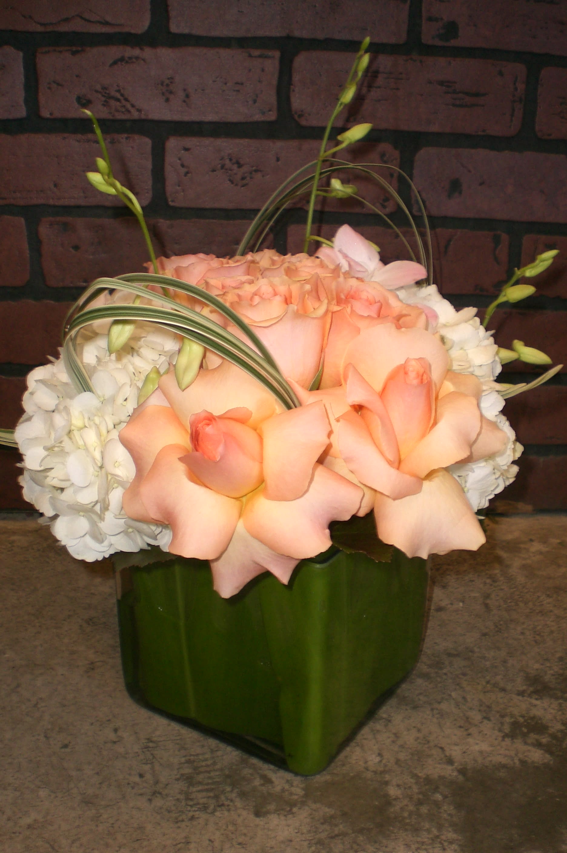 Peach roses and white hydrangeas in a green vase