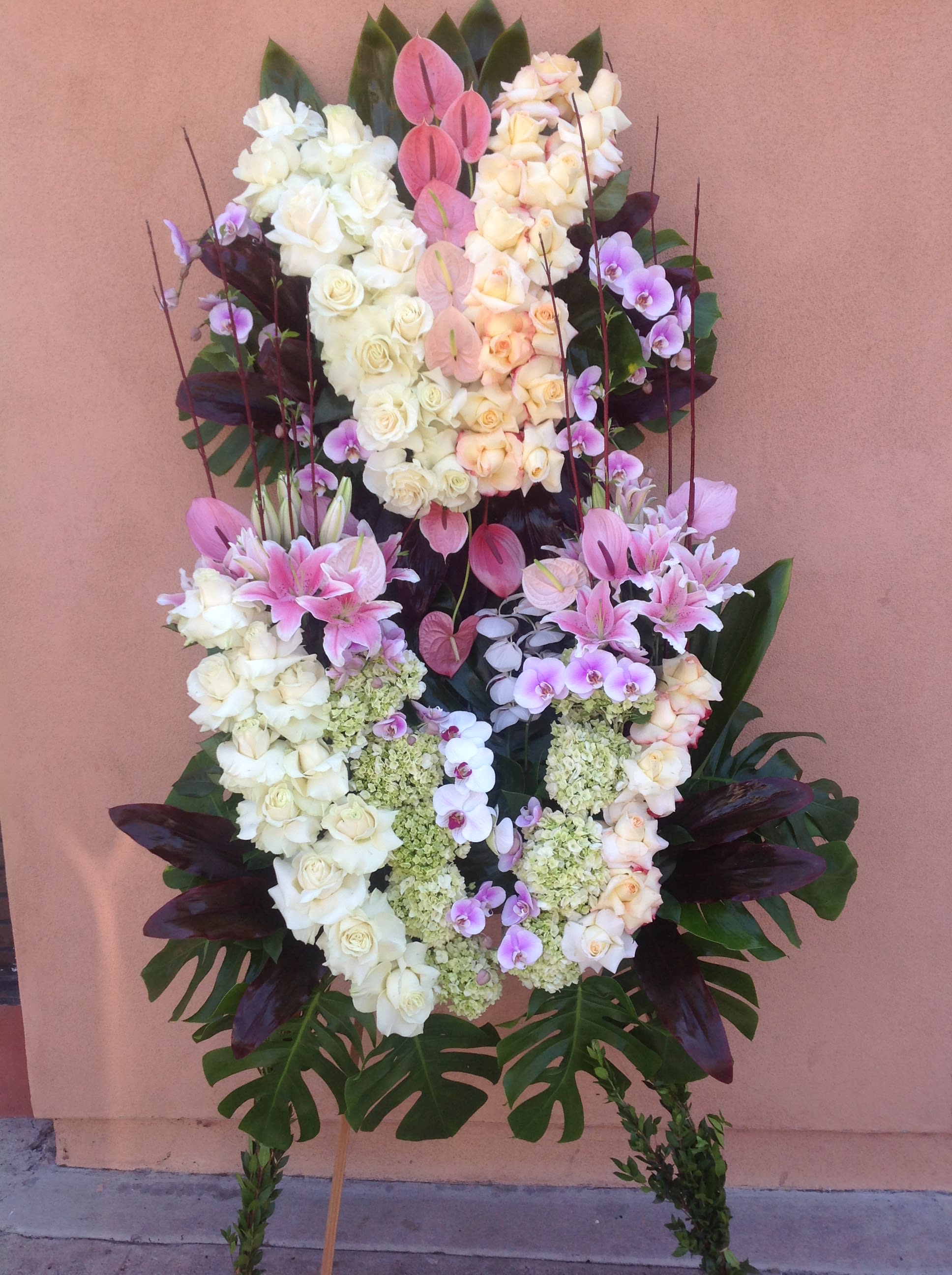 Standing floral funeral spray with white and pink roses, orchids, and lilies