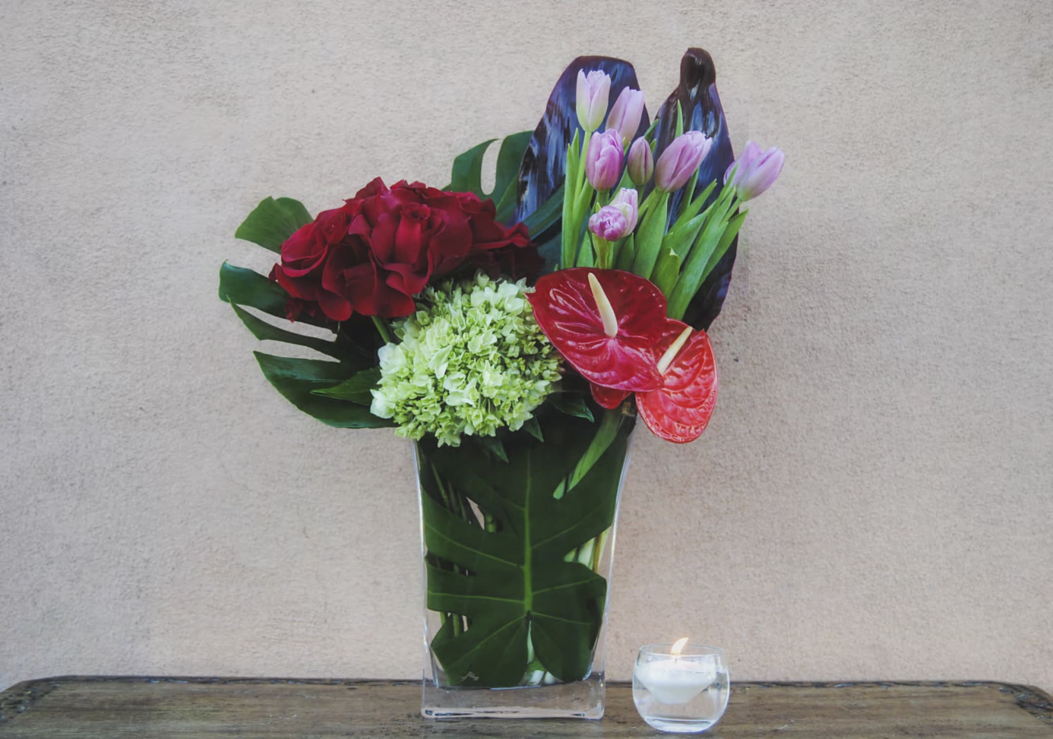 Mixed floral arrangement in a clear vase with red and pink blooms