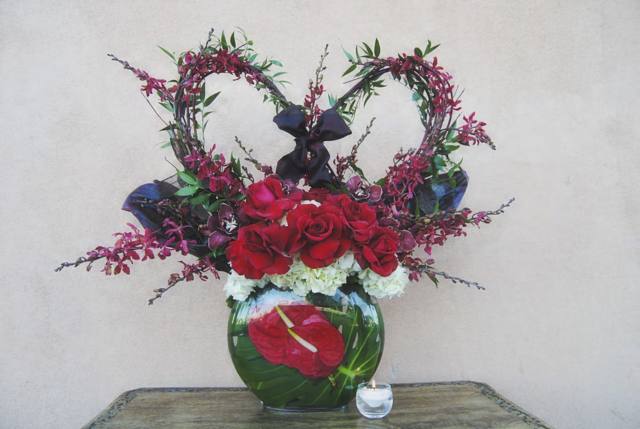 Heart-shaped floral arrangement with red roses in a glass vase