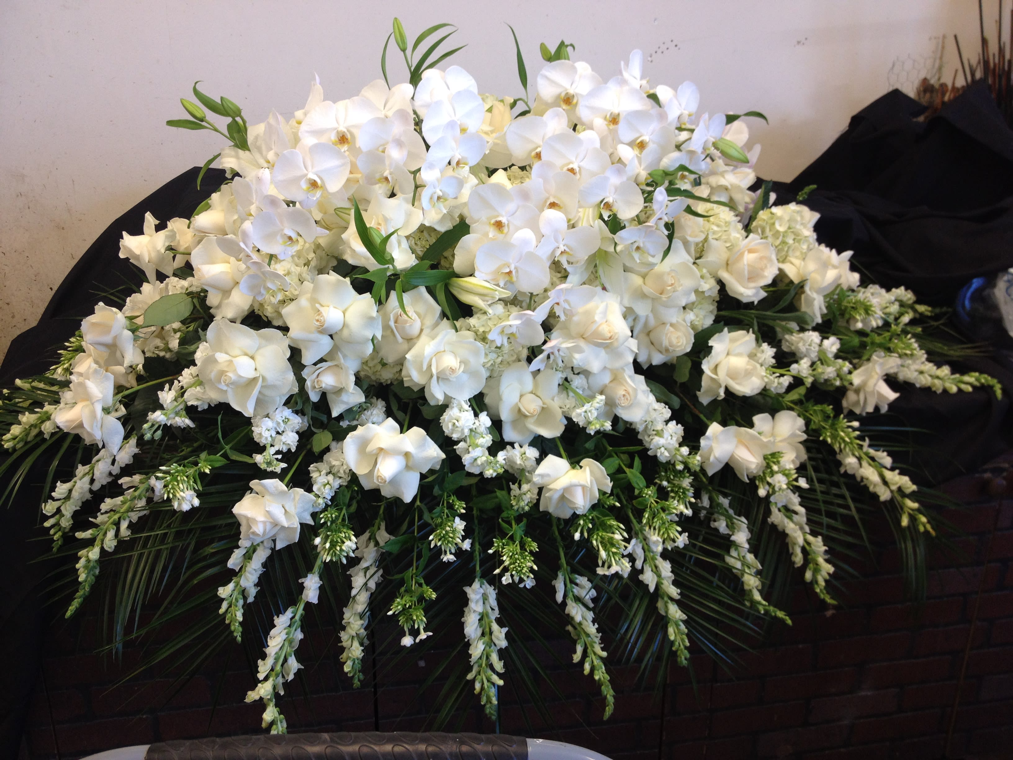 Large white floral arrangement with orchids and roses