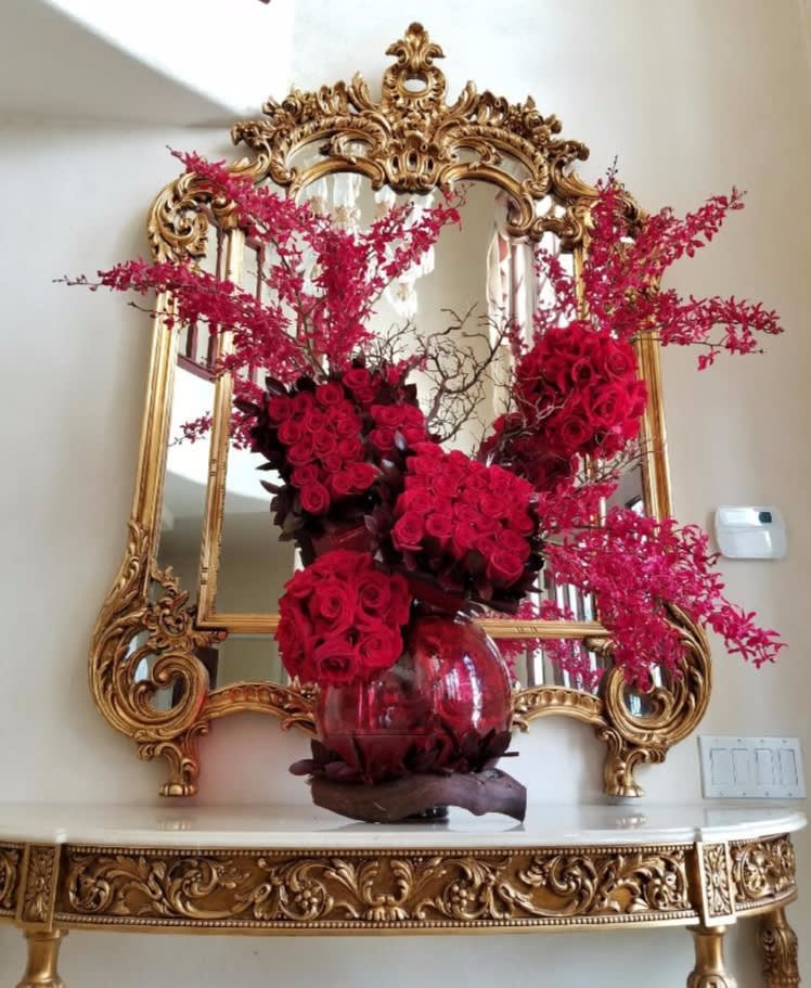 Red rose arrangement in a glass vase with pink branching accents