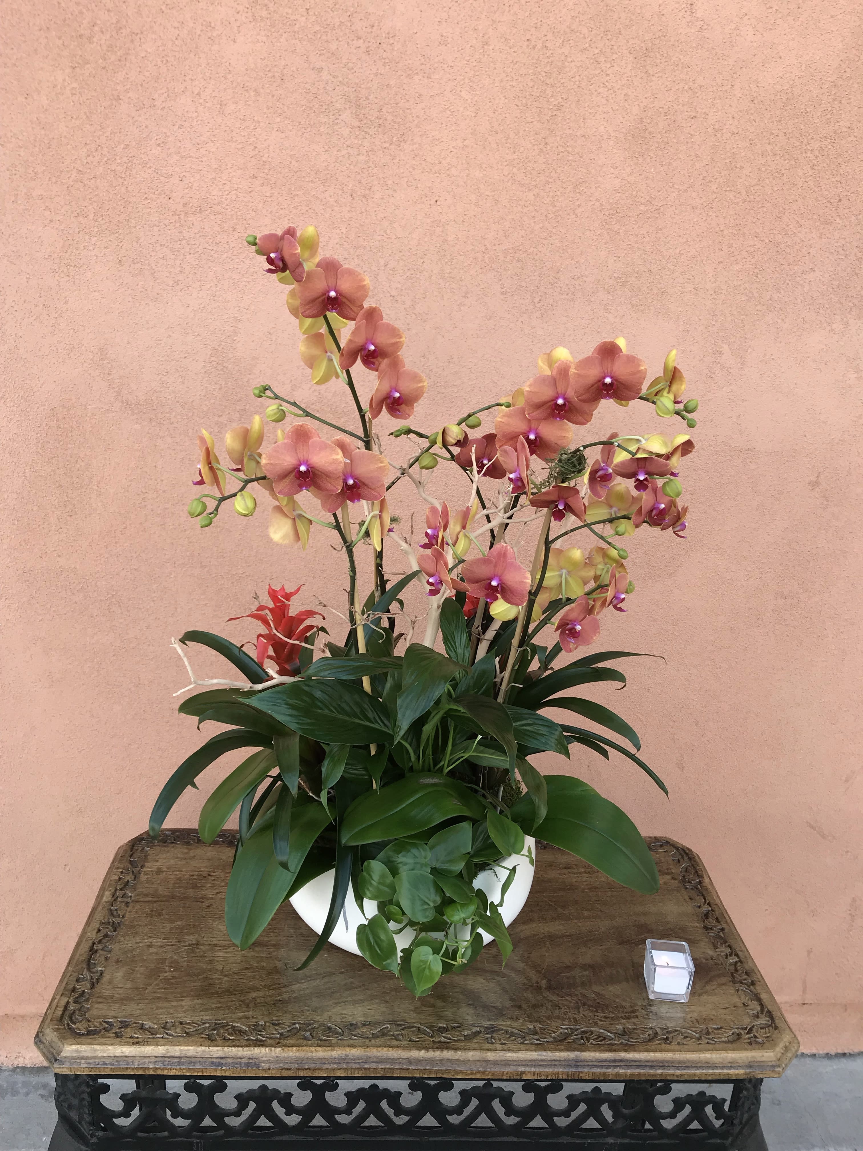 Pink and yellow orchids arranged in a white bowl planter