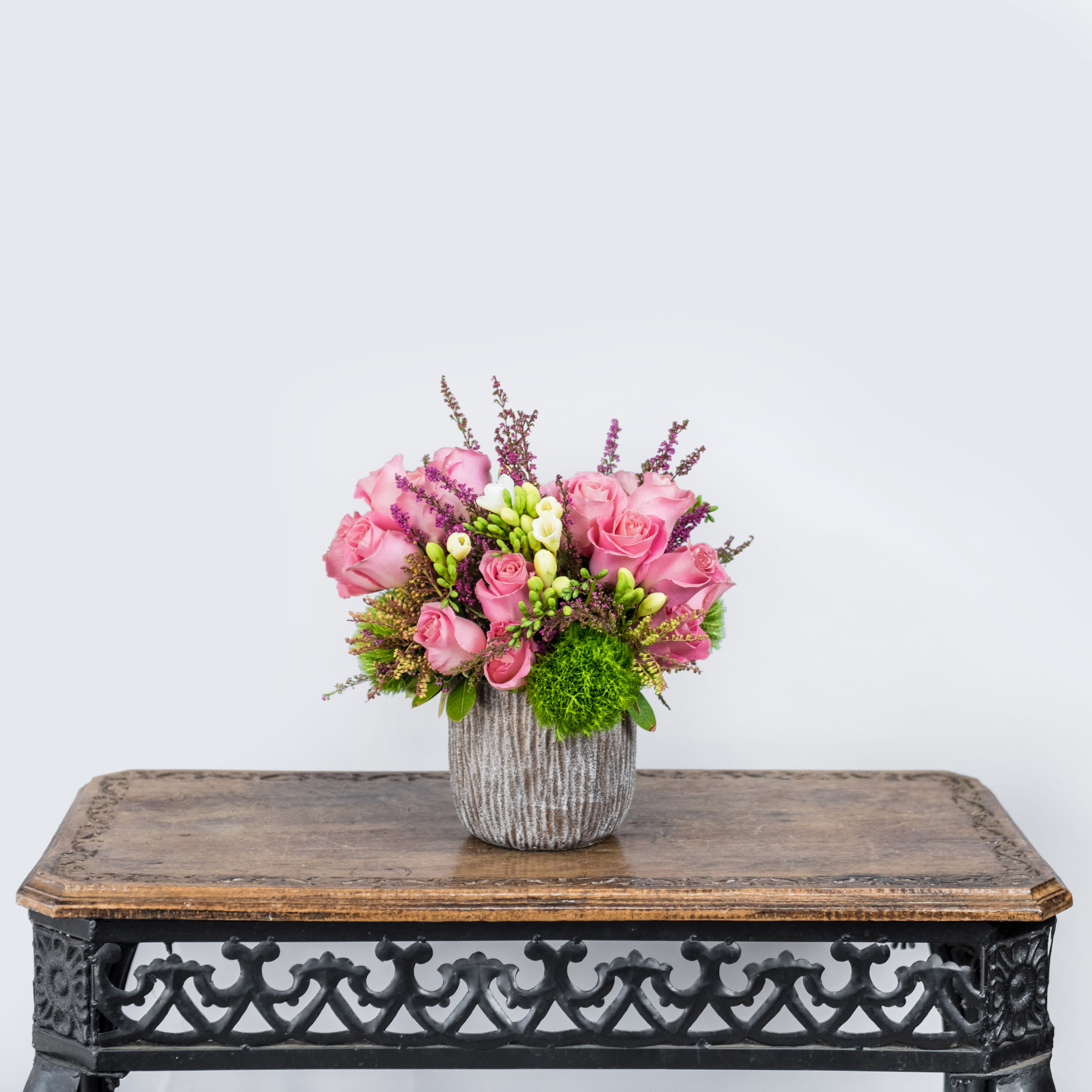 Pink roses arranged in a textured vase on a table